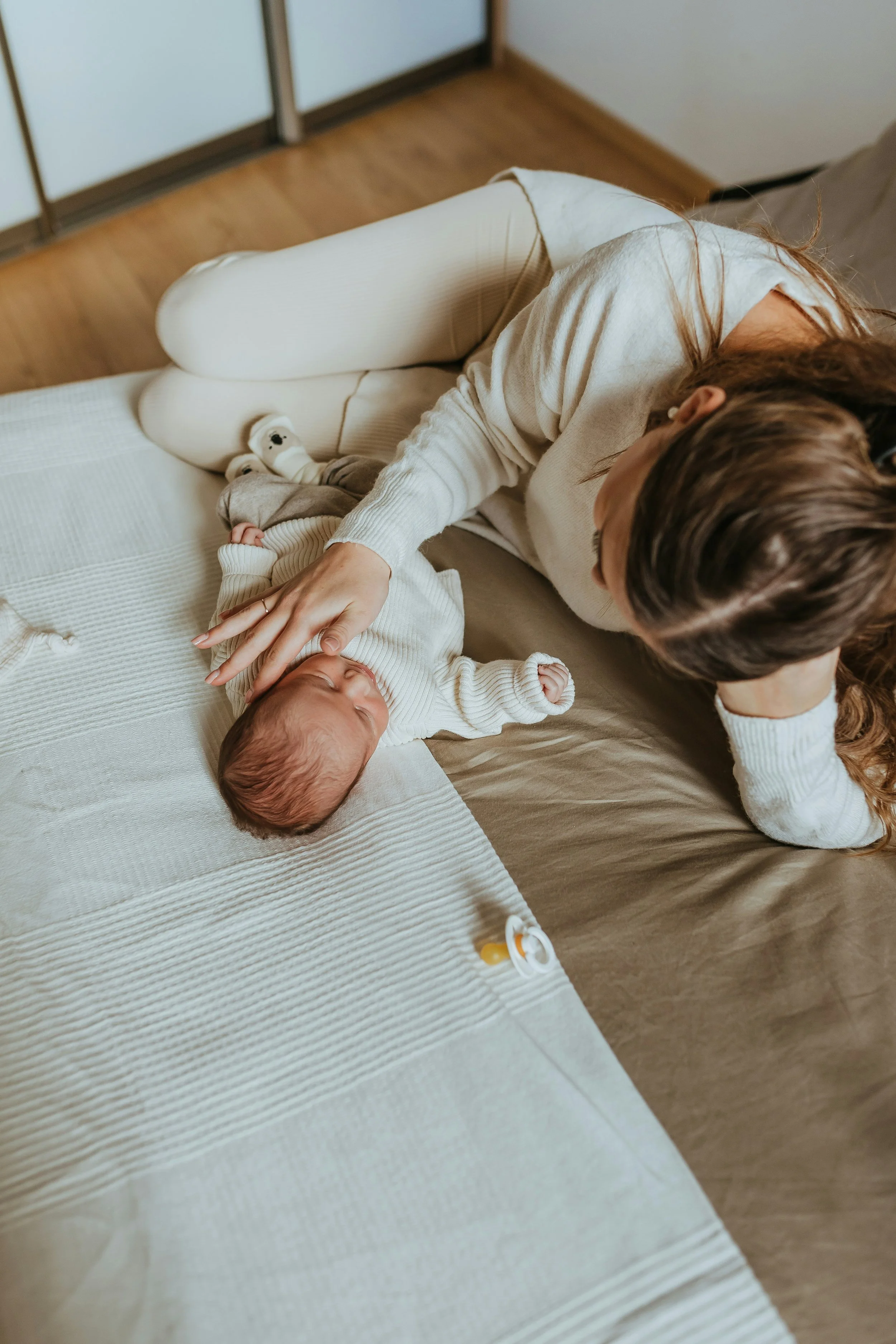 Mom laying on a bed with baby in her home in Los Angeles California. Alexa Levine specializes in therapy for new moms during the postpartum period.