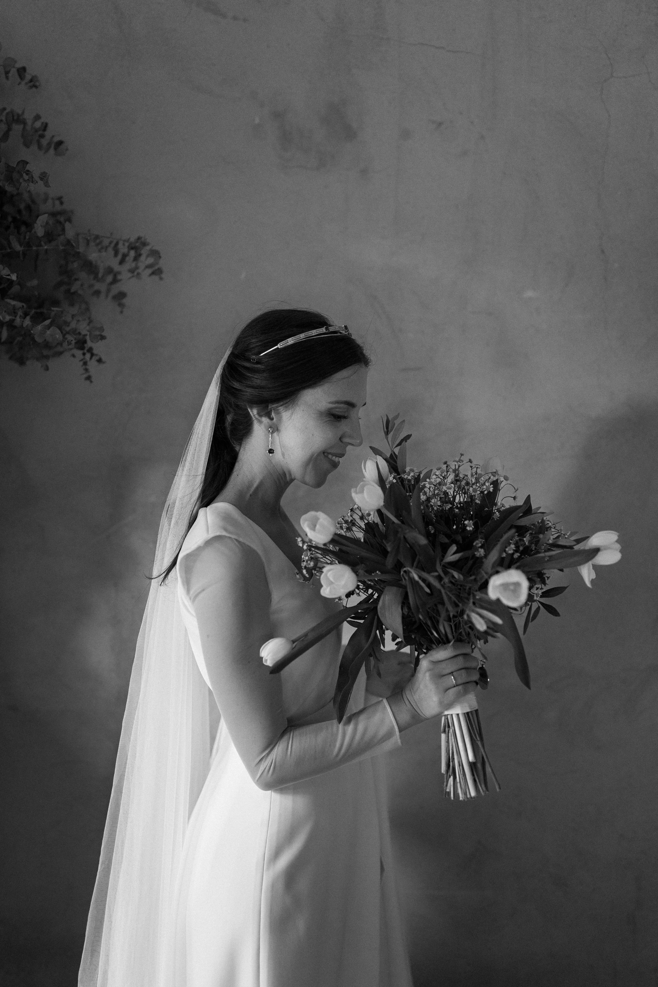 Mujer vestida de novia sosteniendo un ramo de flores, sonriente.