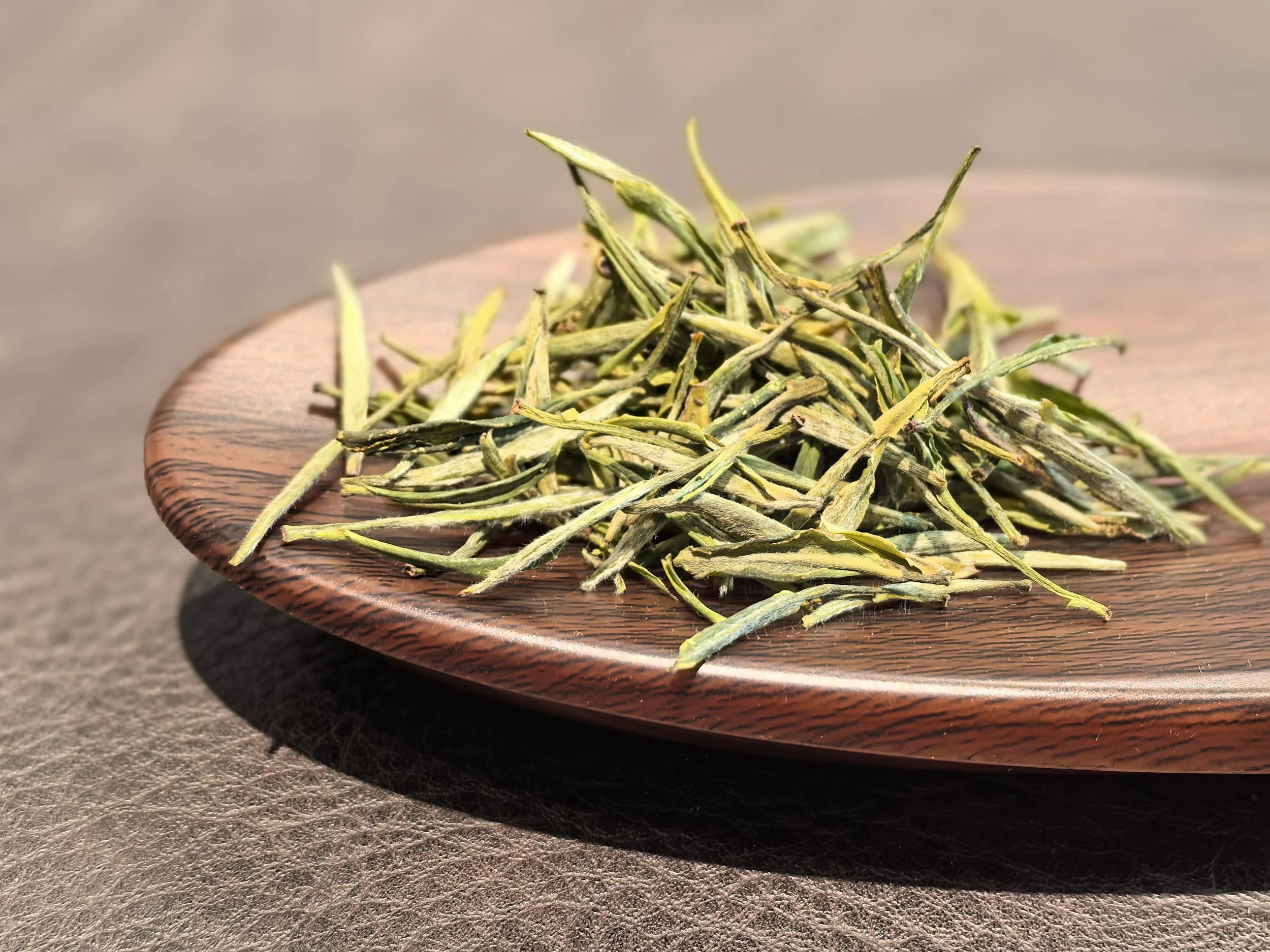 Dried green tea leaves on a wooden plate