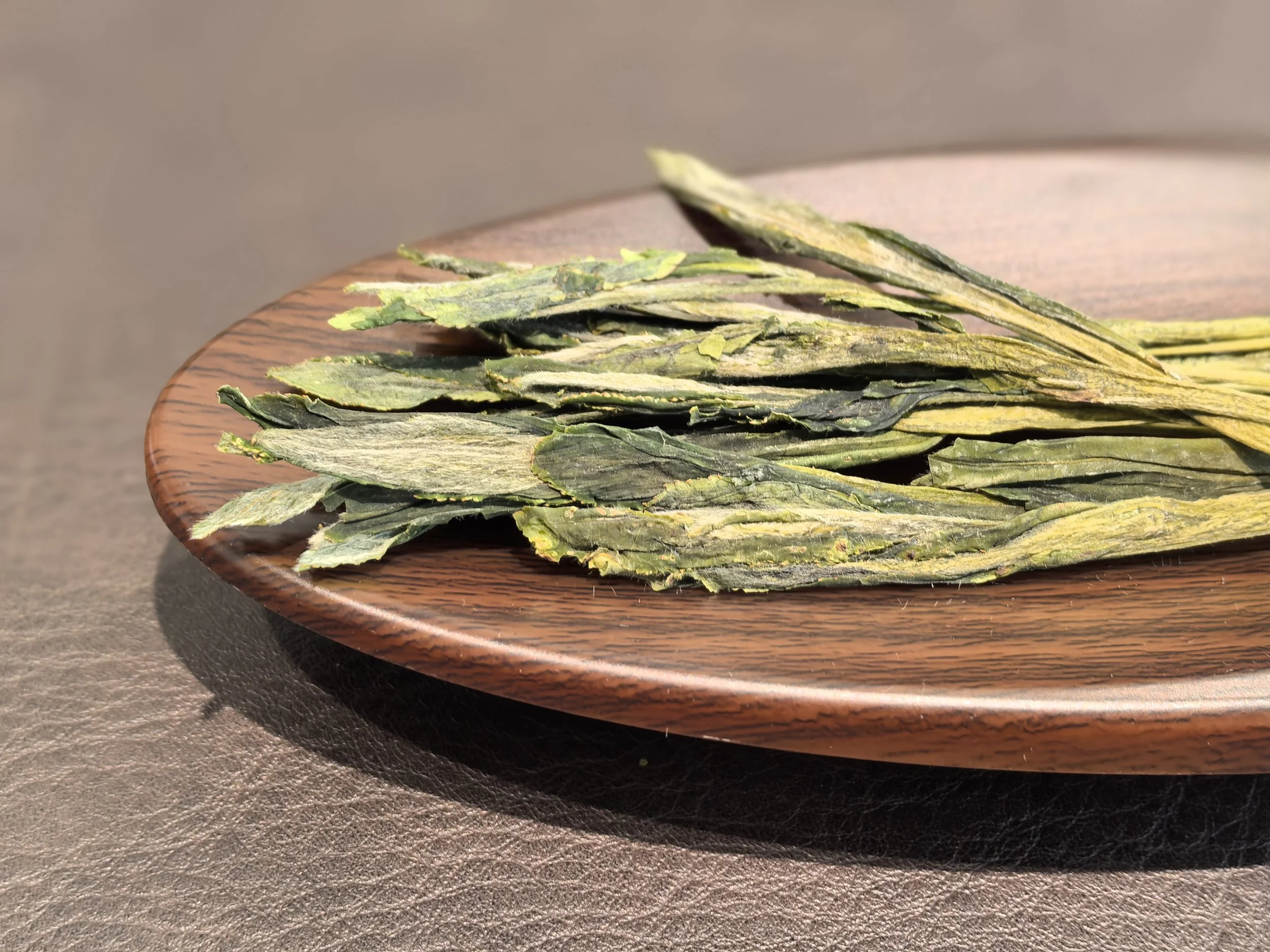 Dried green and yellow herbs on a wooden plate.