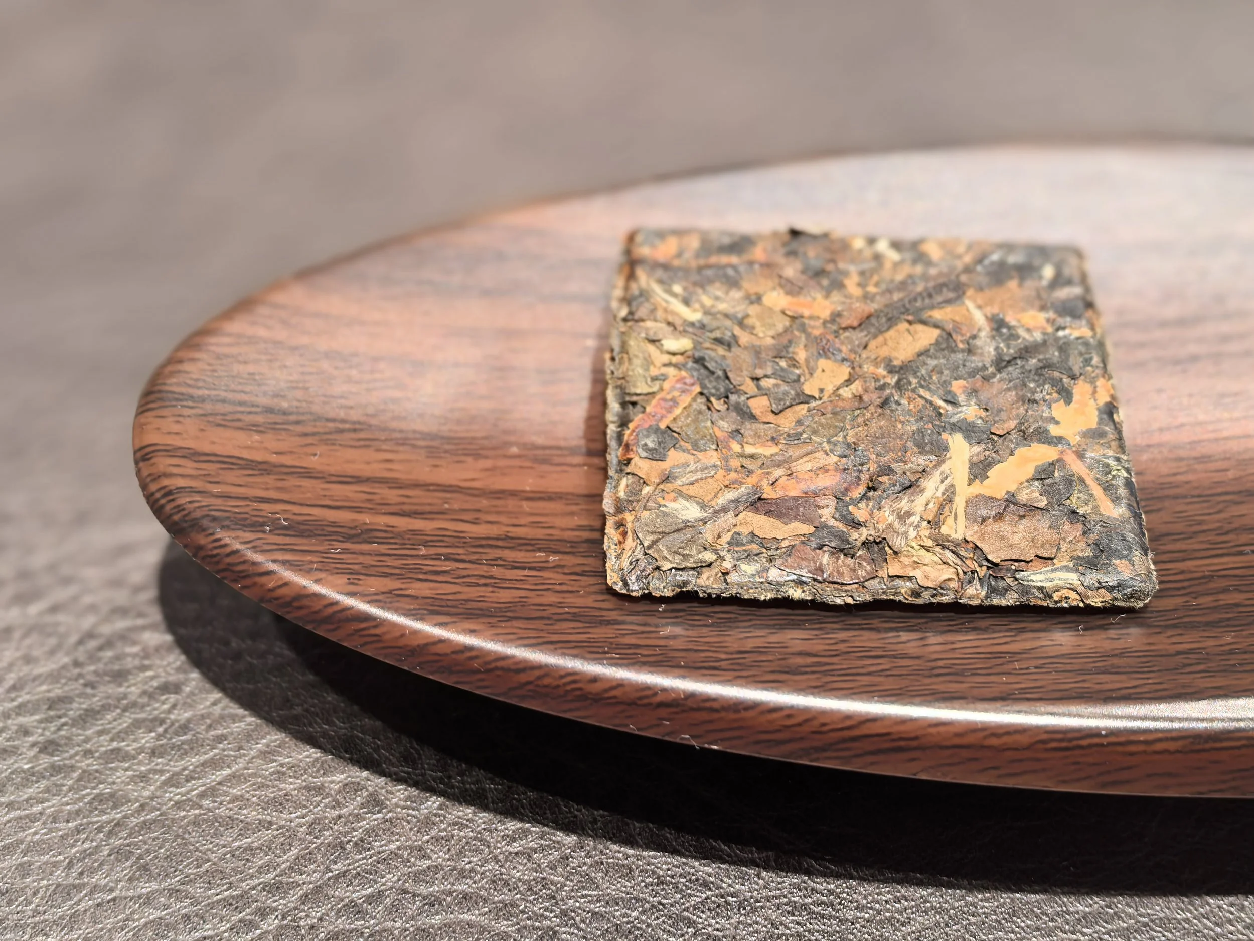 2017 Chenpi aged white tea placed on a round, polished wooden plate.