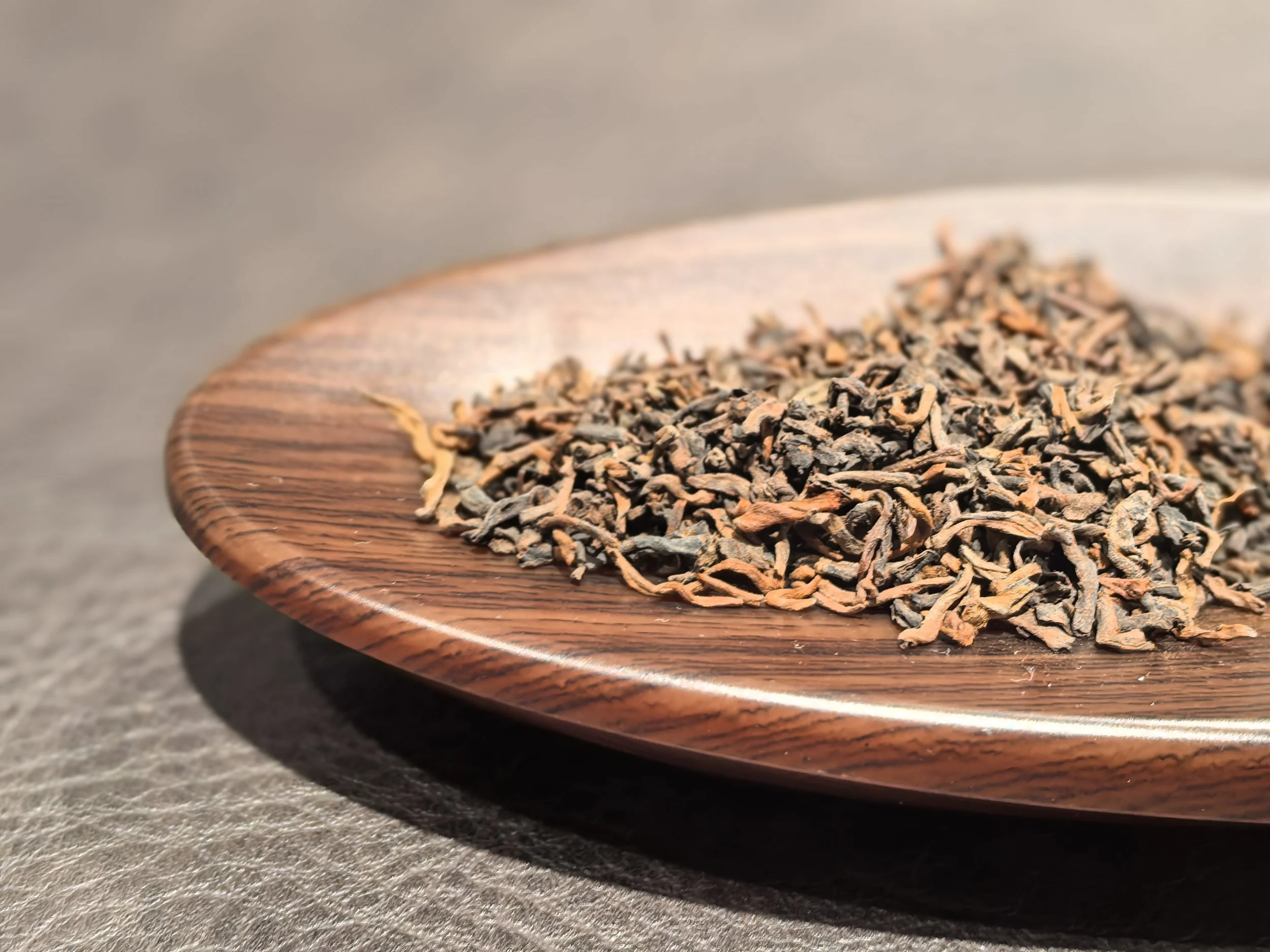 Dried black tea leaves on a wooden plate