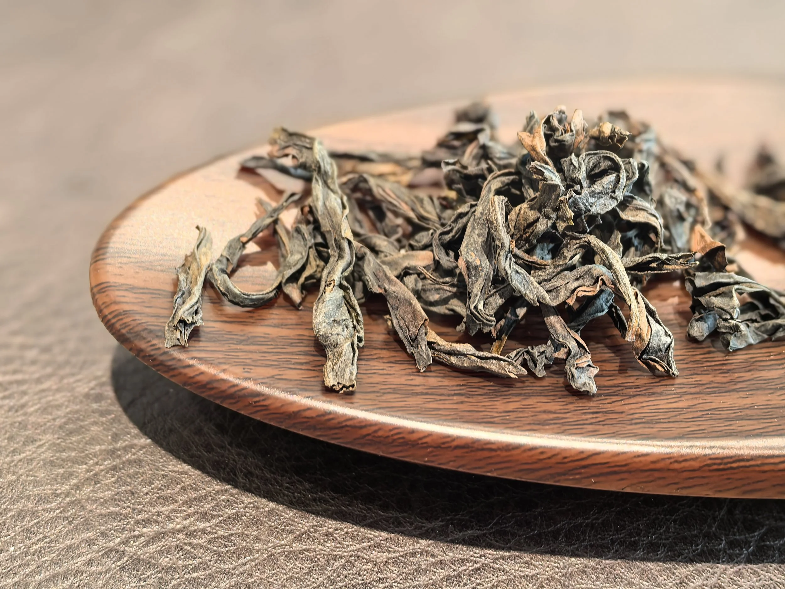 Dried loose leaf tea on a wooden plate