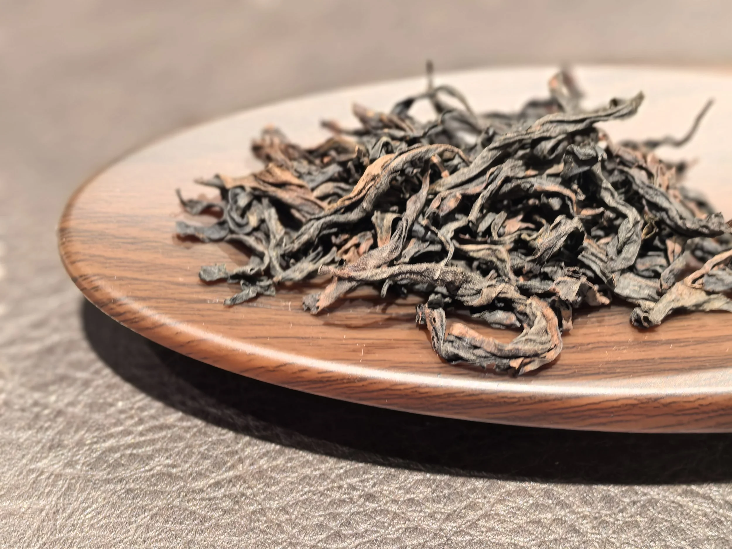 Dried tea leaves on a wooden plate.
