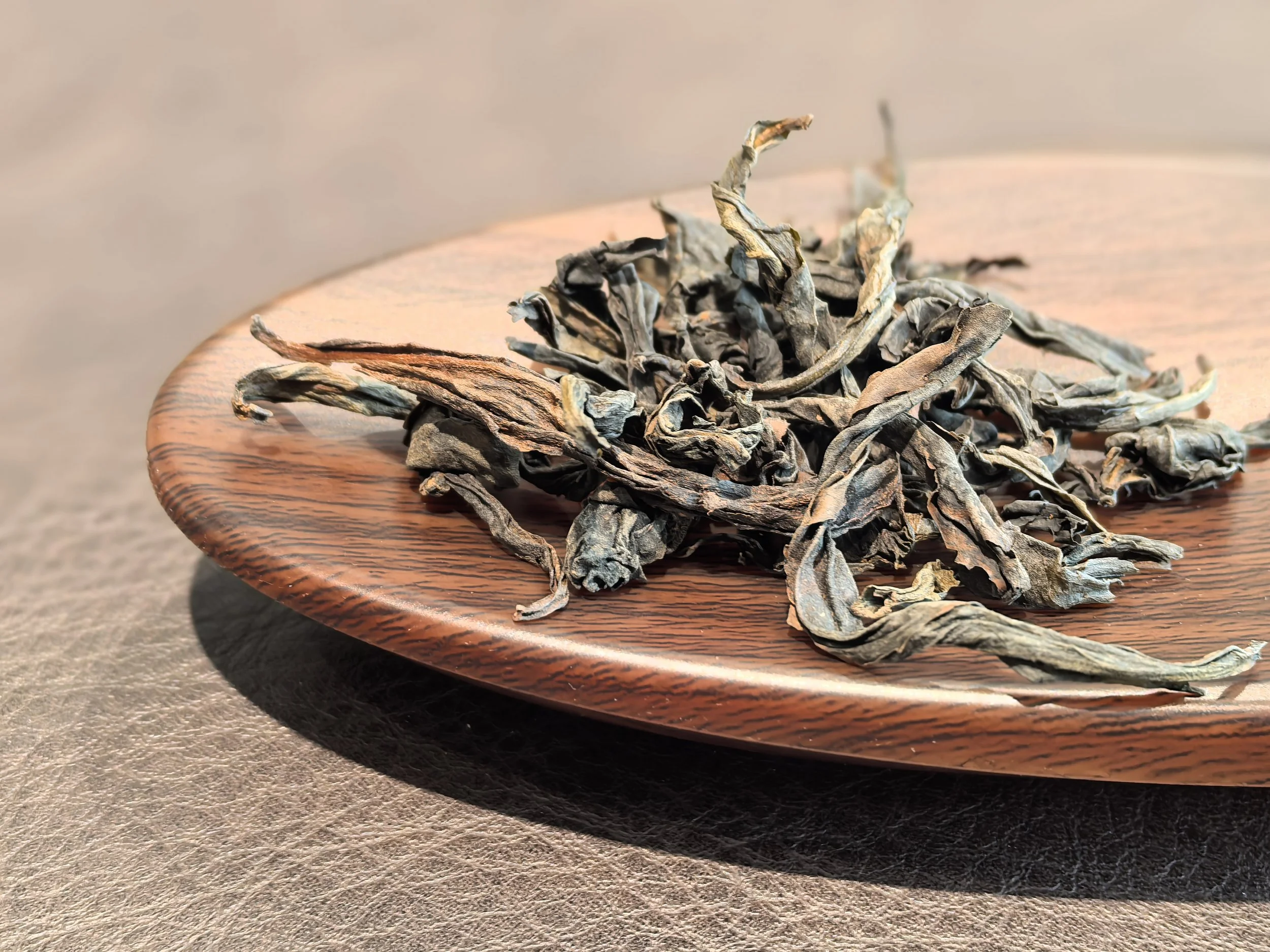 Dried tea leaves on a wooden plate.