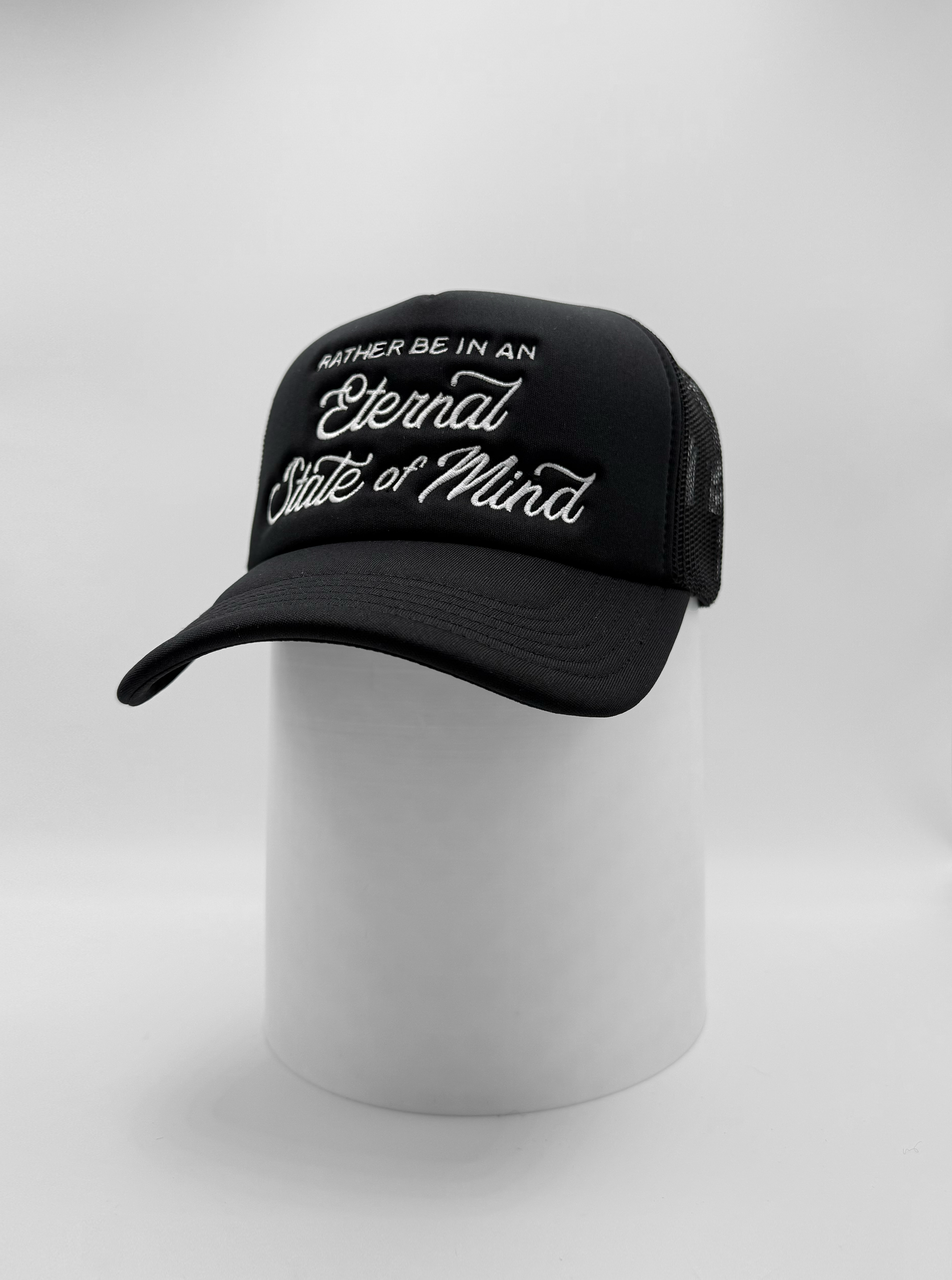 Black foam trucker hat with white embroidered text that reads “I’d Rather Be in an Eternal State of Mind."