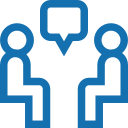 Scenic landscape with a calm lake, green hills, and rugged mountains in the background under a cloudy sky.