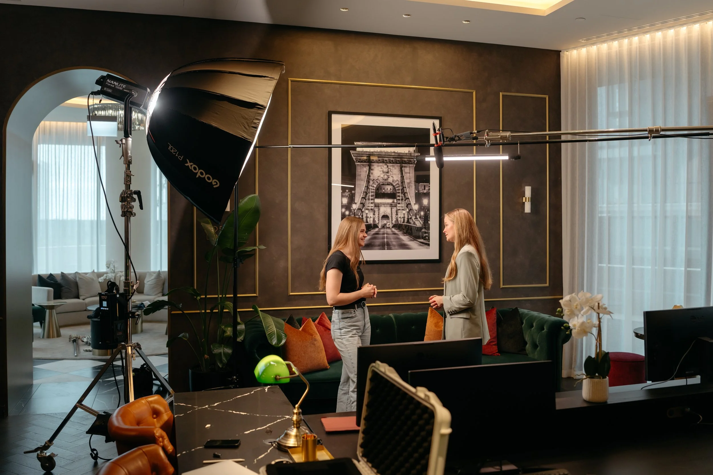 On set of a client testimonial video, the image shows two women talking with professional lighting and cameras.
