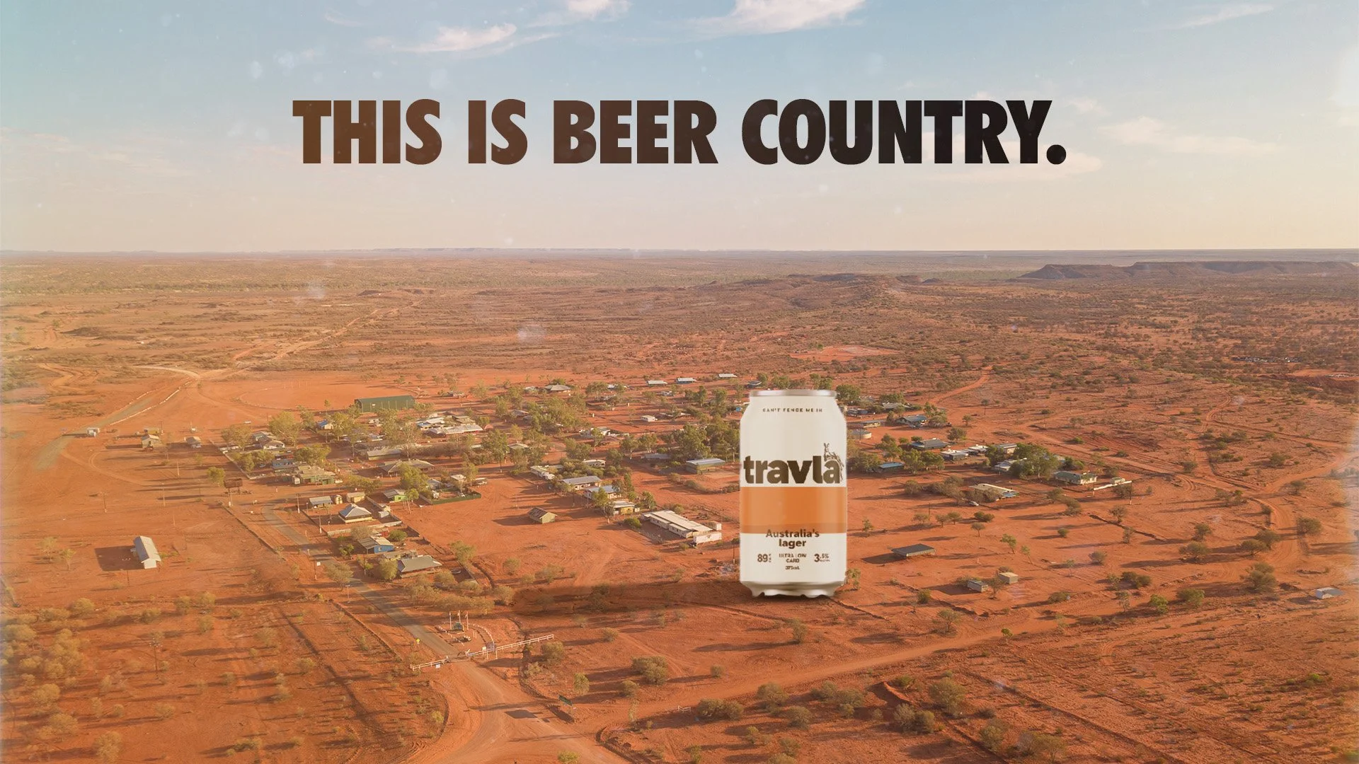An aerial view of an Australian town or settlement in a desert landscape with a large can of Travla beer in the foreground. Text on the image reads, 'This is Beer Country.'