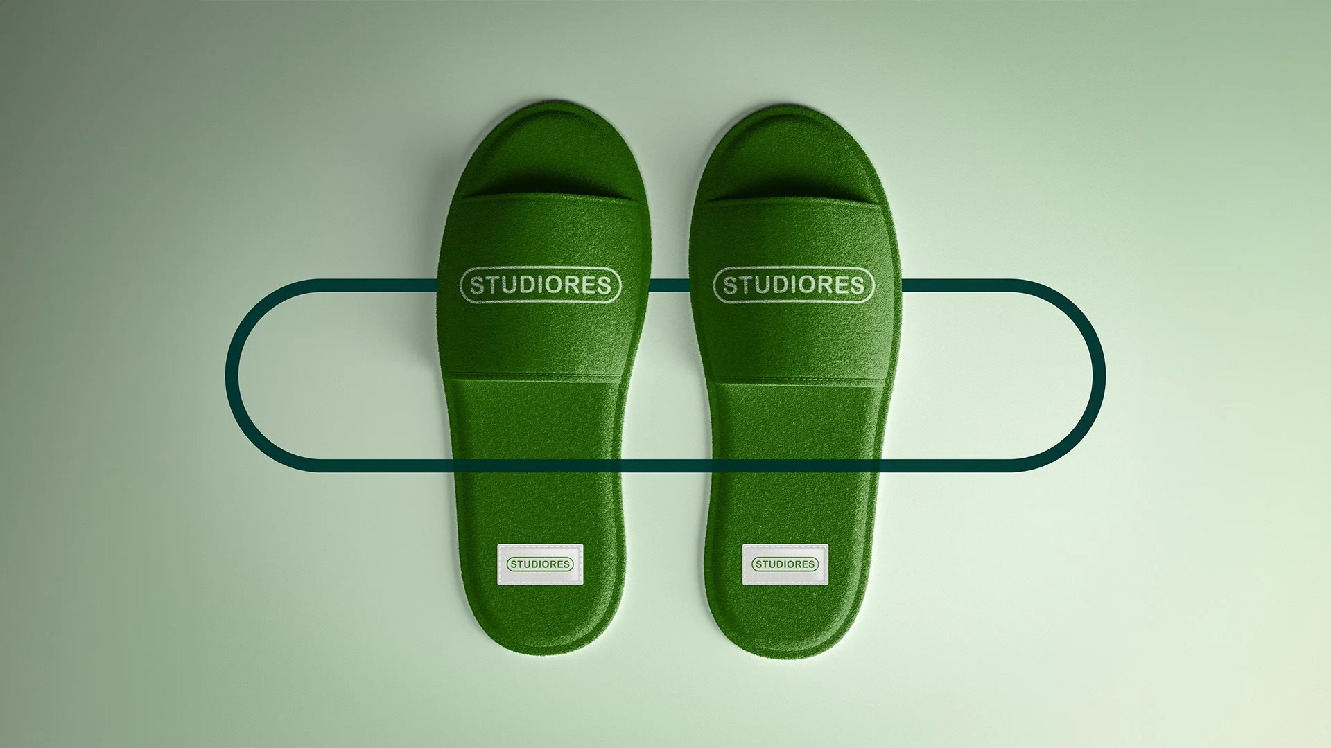 Pair of green slippers with the word "STUDIORES" printed on them, placed on a light green background with an outlined oval and line design.