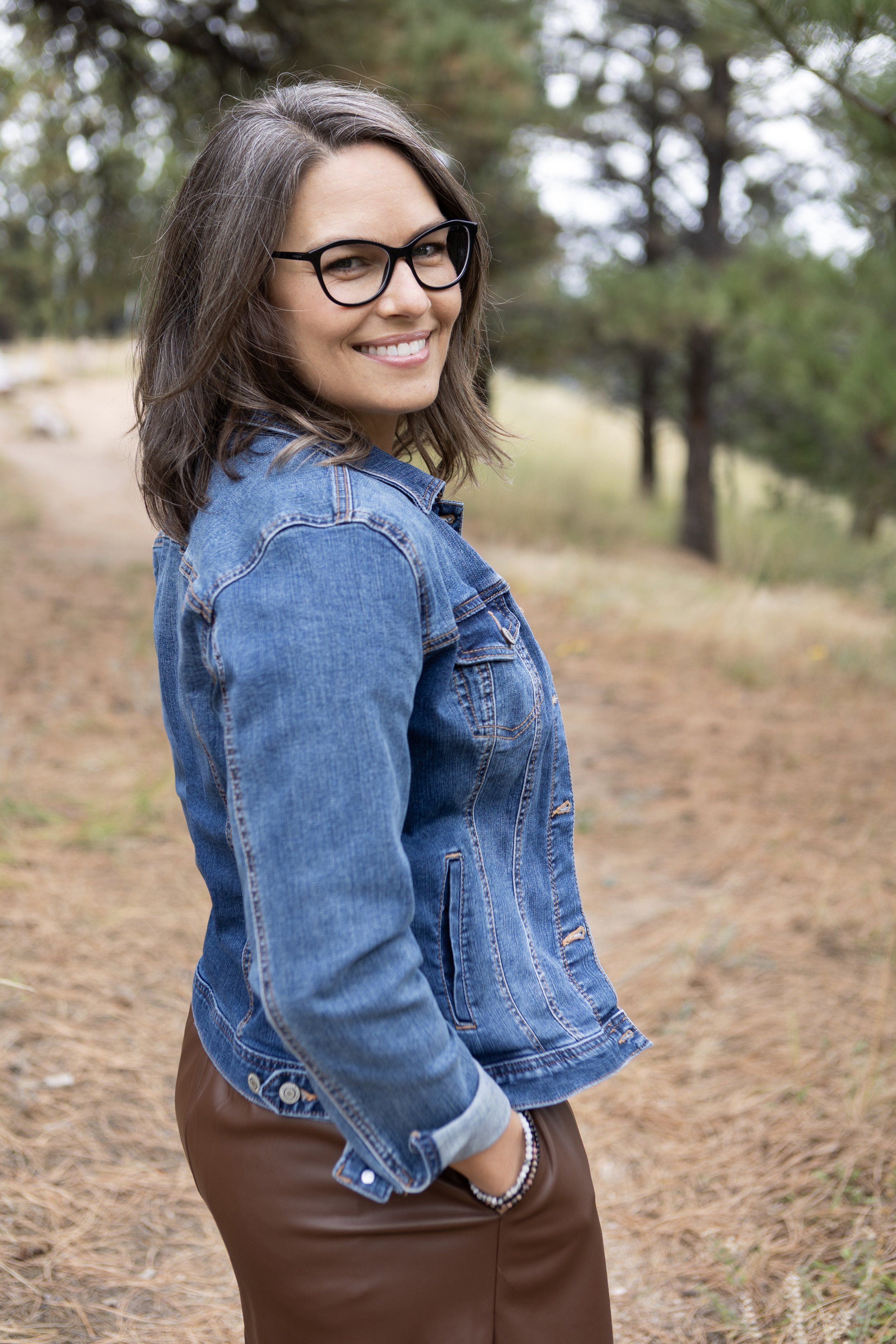 Woman in a jean jacket on a wooded path