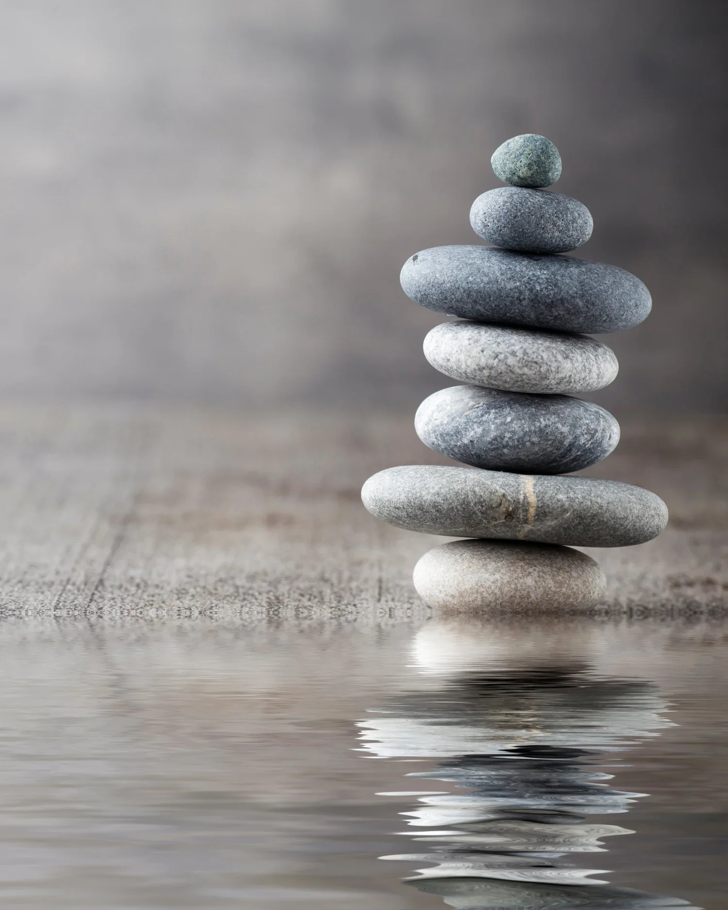 A balanced stack of stones by calm water, symbolizing the physical and emotional alignment achieved through a Body Code session.
