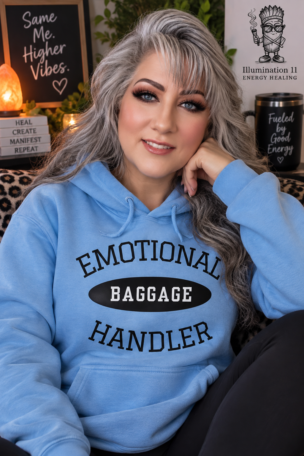Tracey McQuinn of Illumination 11 Energy Healing wearing a blue Emotional Baggage Handler hoodie, showcasing her humorous emotional healing merchandise inspired by the Emotion Code and releasing emotional baggage.