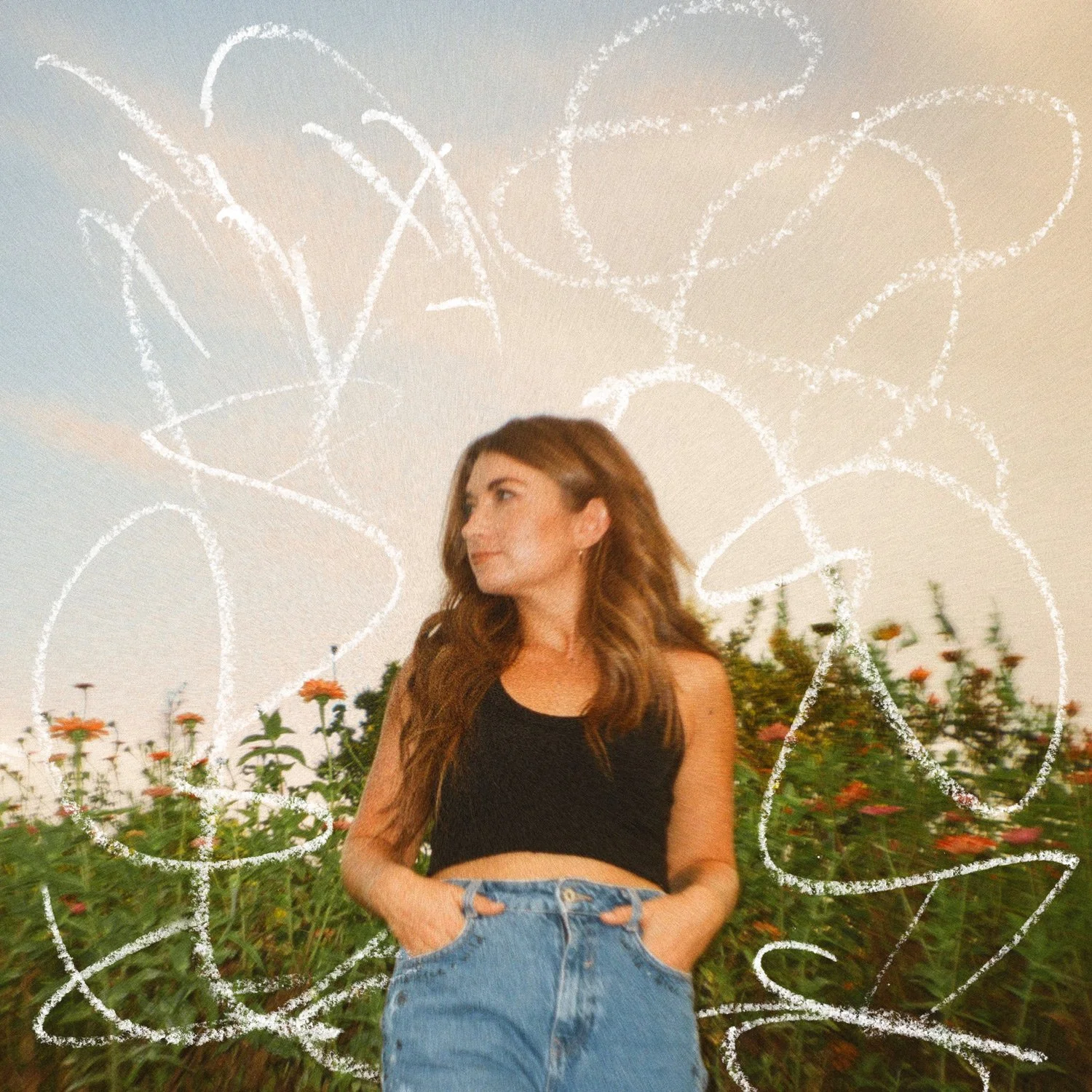 A young woman with long hair, wearing a black sleeveless top and high-waisted blue jeans, stands in front of a field of flowers, with chalk-drawn butterfly wings behind her on the sky.