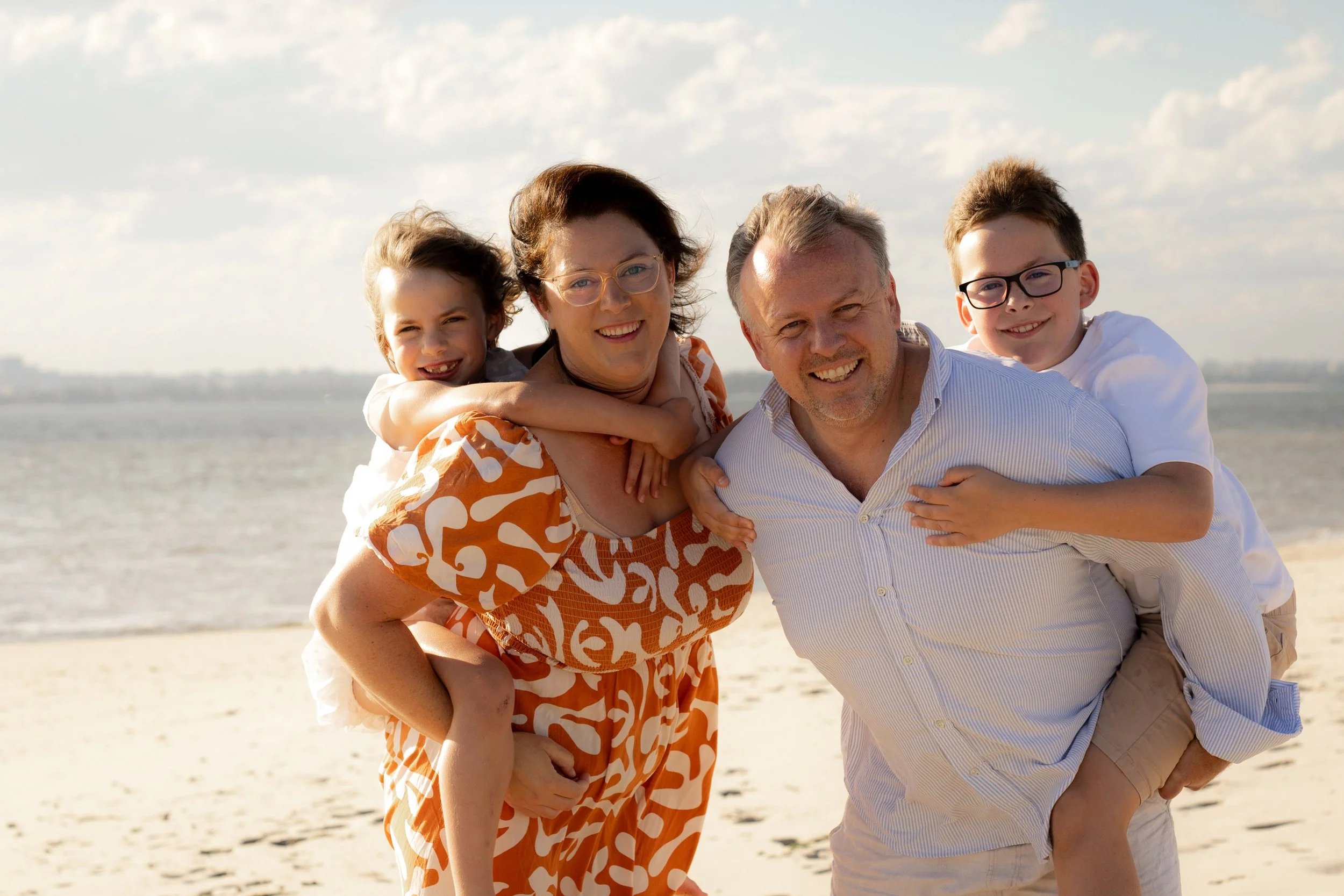 Family of four laughing together during a sunset beach photoshoot in the Sutherland Shire.