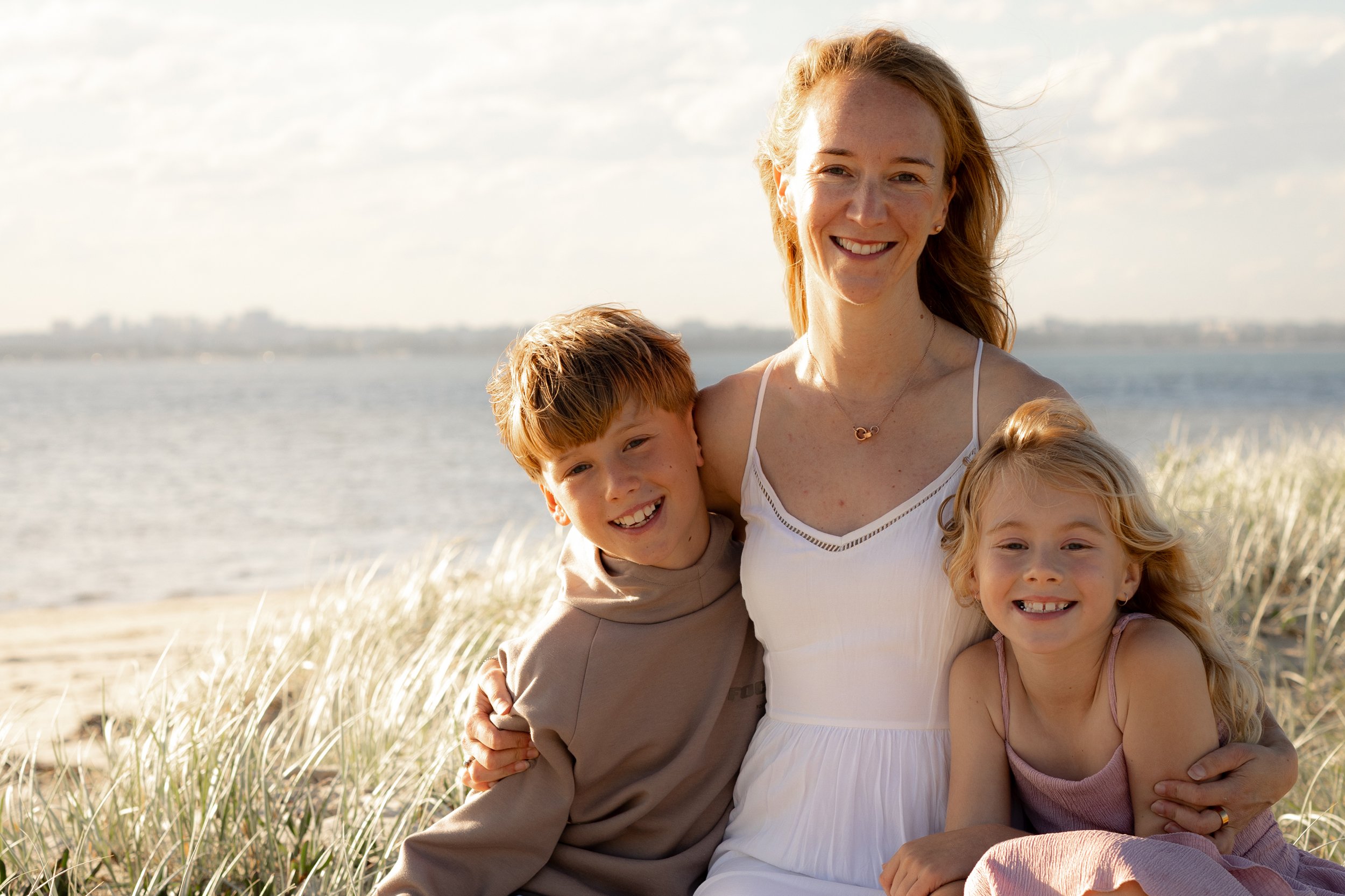 Mother posing with her two children among the beach grass during a sunset Christmas mini photo session near Cronulla.
