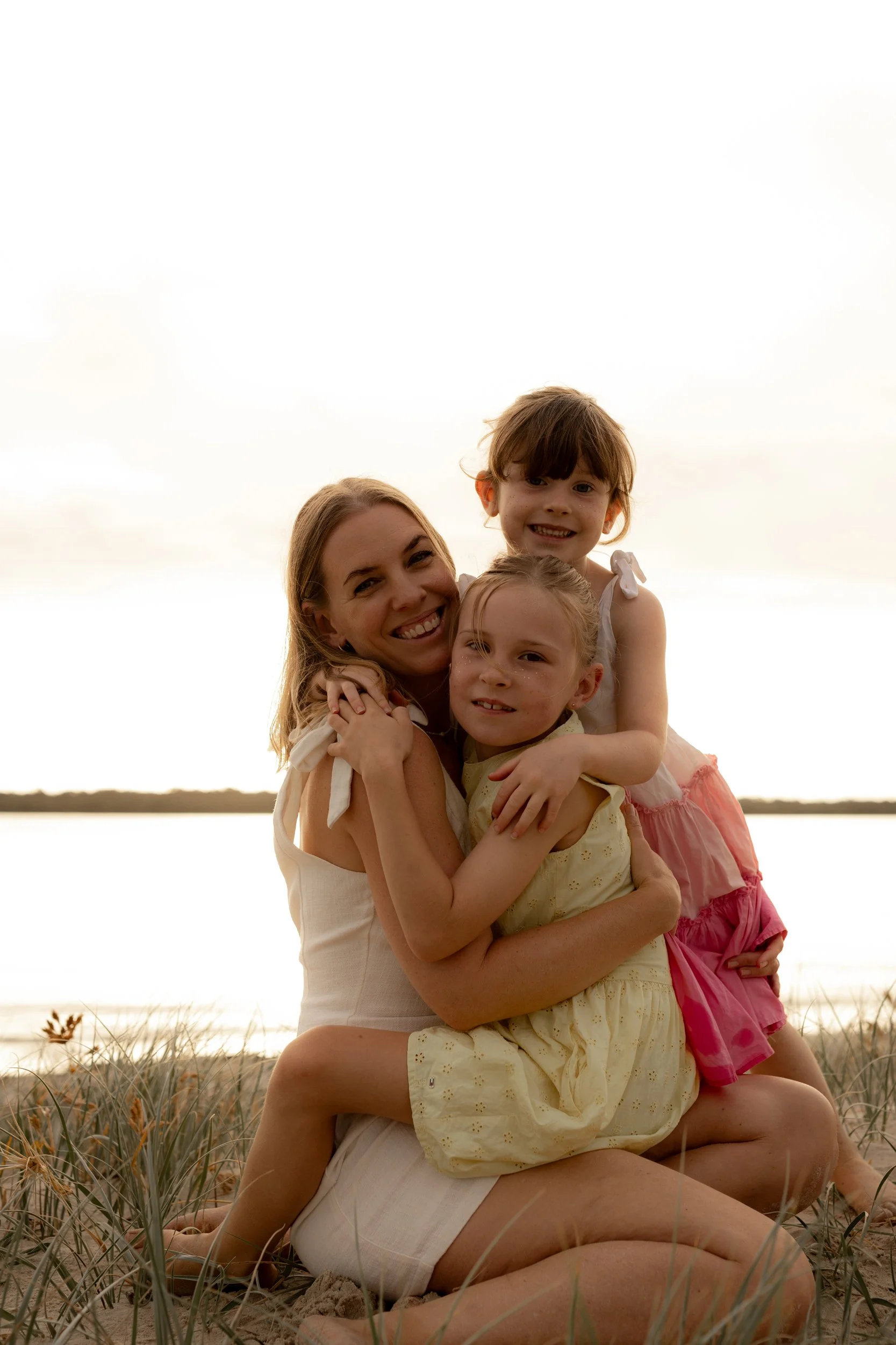 Mum embracing her two young daughters in a beautiful beach family portrait at sunset in the Sutherland Shire.