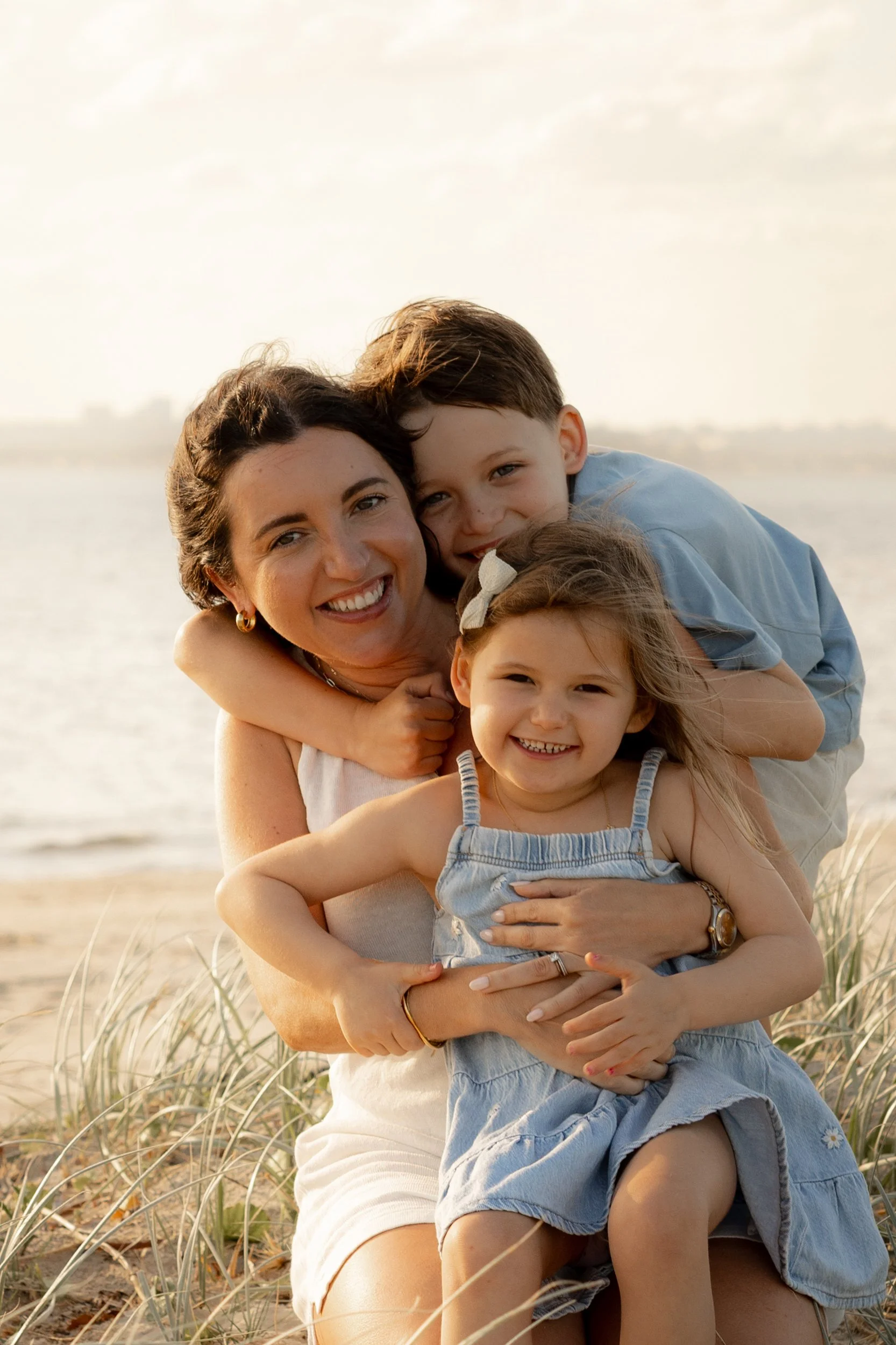 Mother surrounded by her two smiling kids during a Christmas family beach photoshoot in Kurnell.