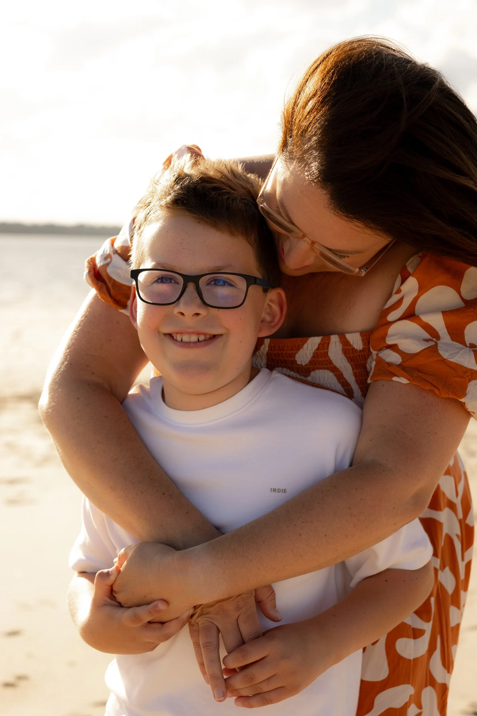 Mother and two children sitting with their family dog among the beach grass during a Christmas mini session in Kurnell.