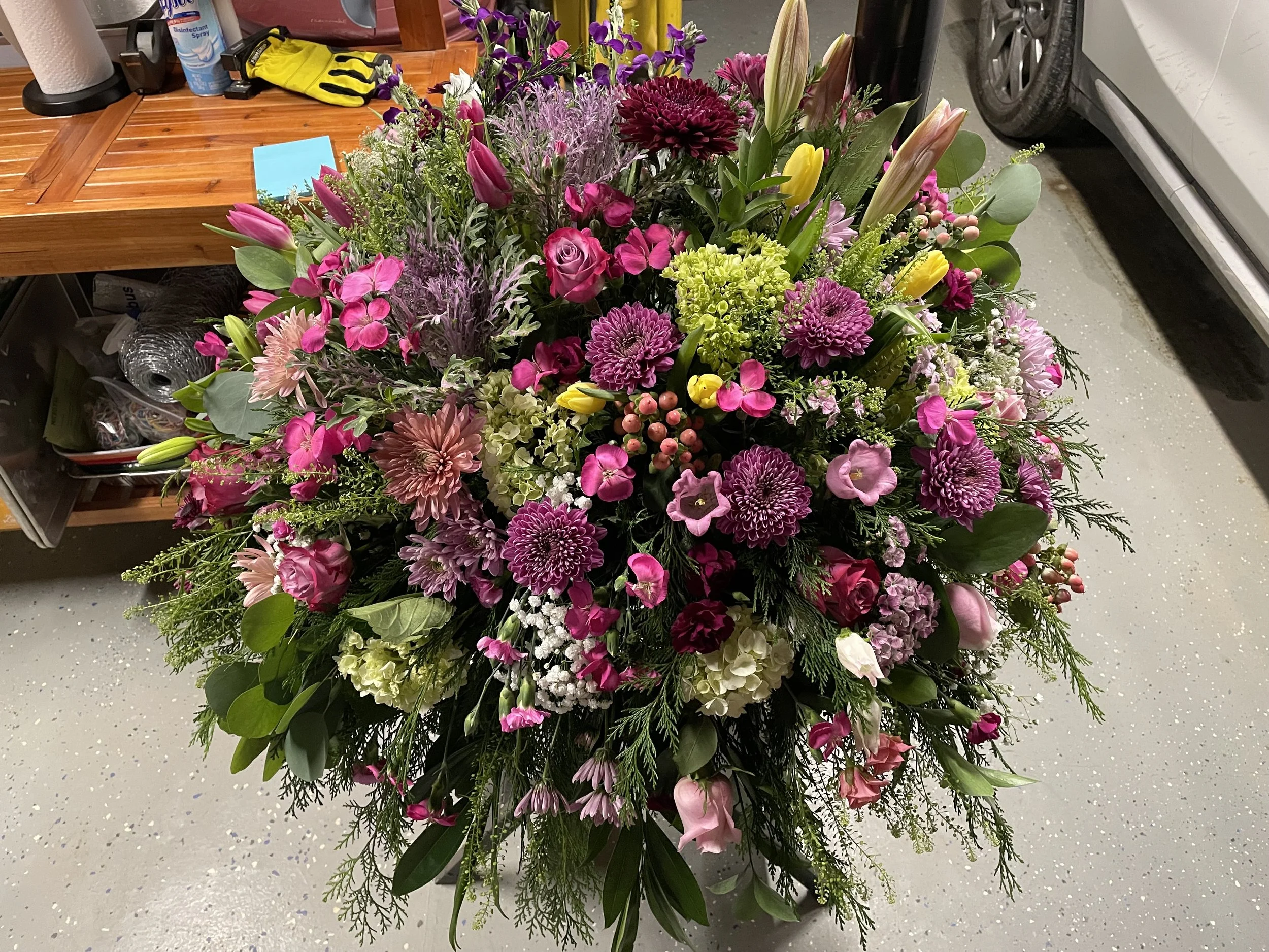 A large bouquet of pink, purple, yellow, and white flowers with green foliage in a decorative arrangement.