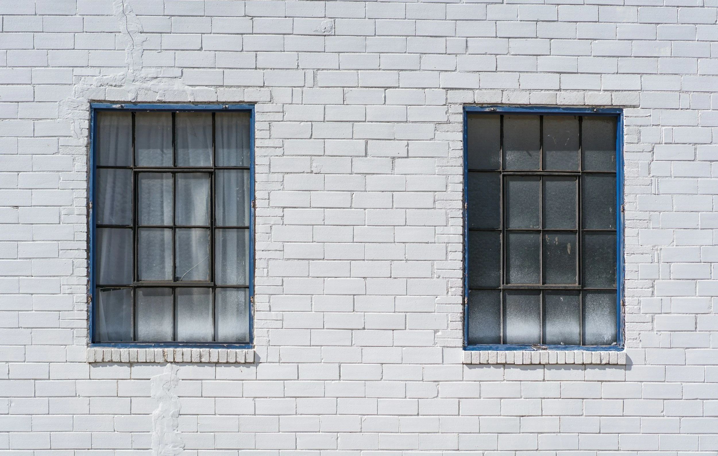 Two old-fashioned windows on a white brick wall.