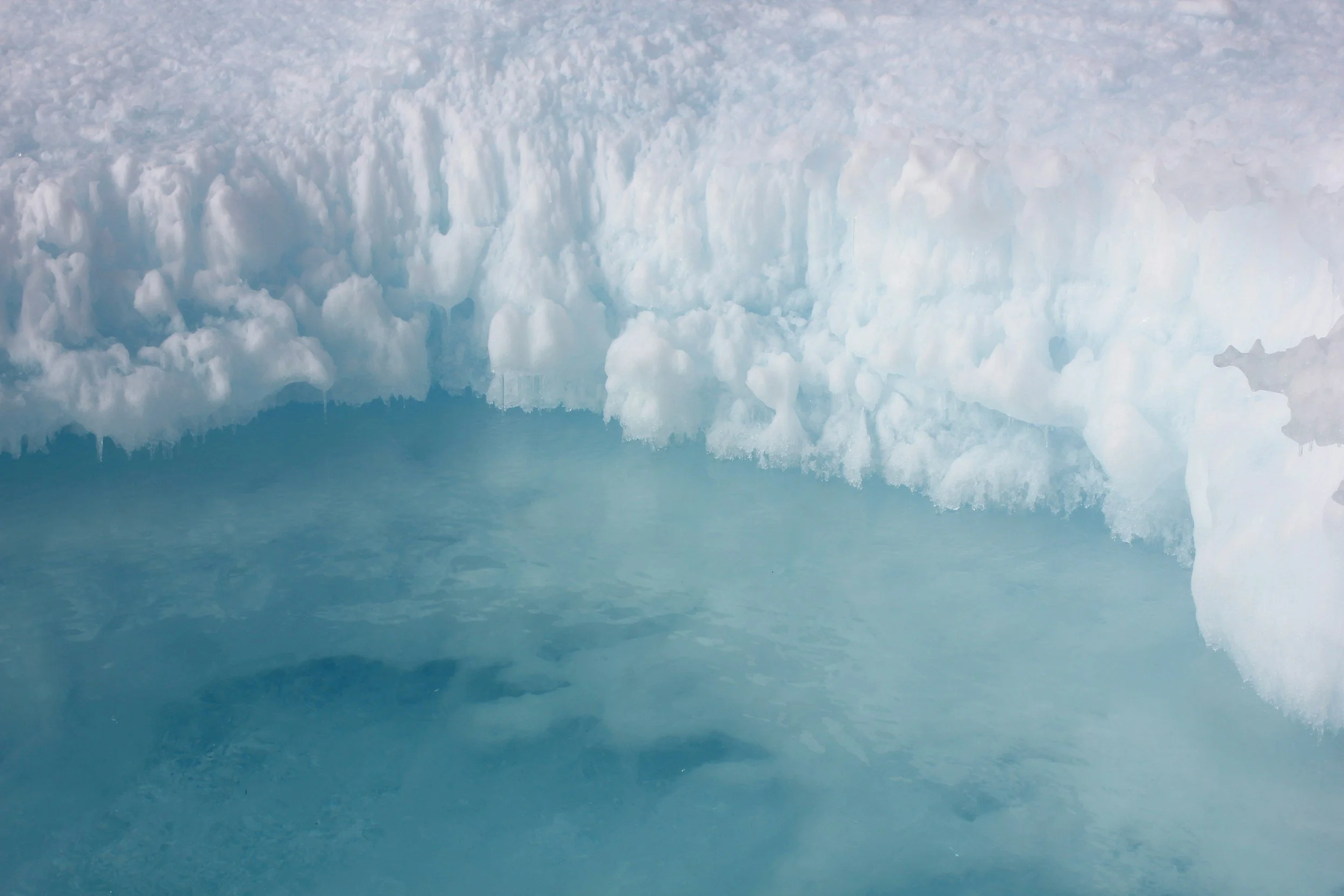 Close-up of icy snowbank and frozen water surface
