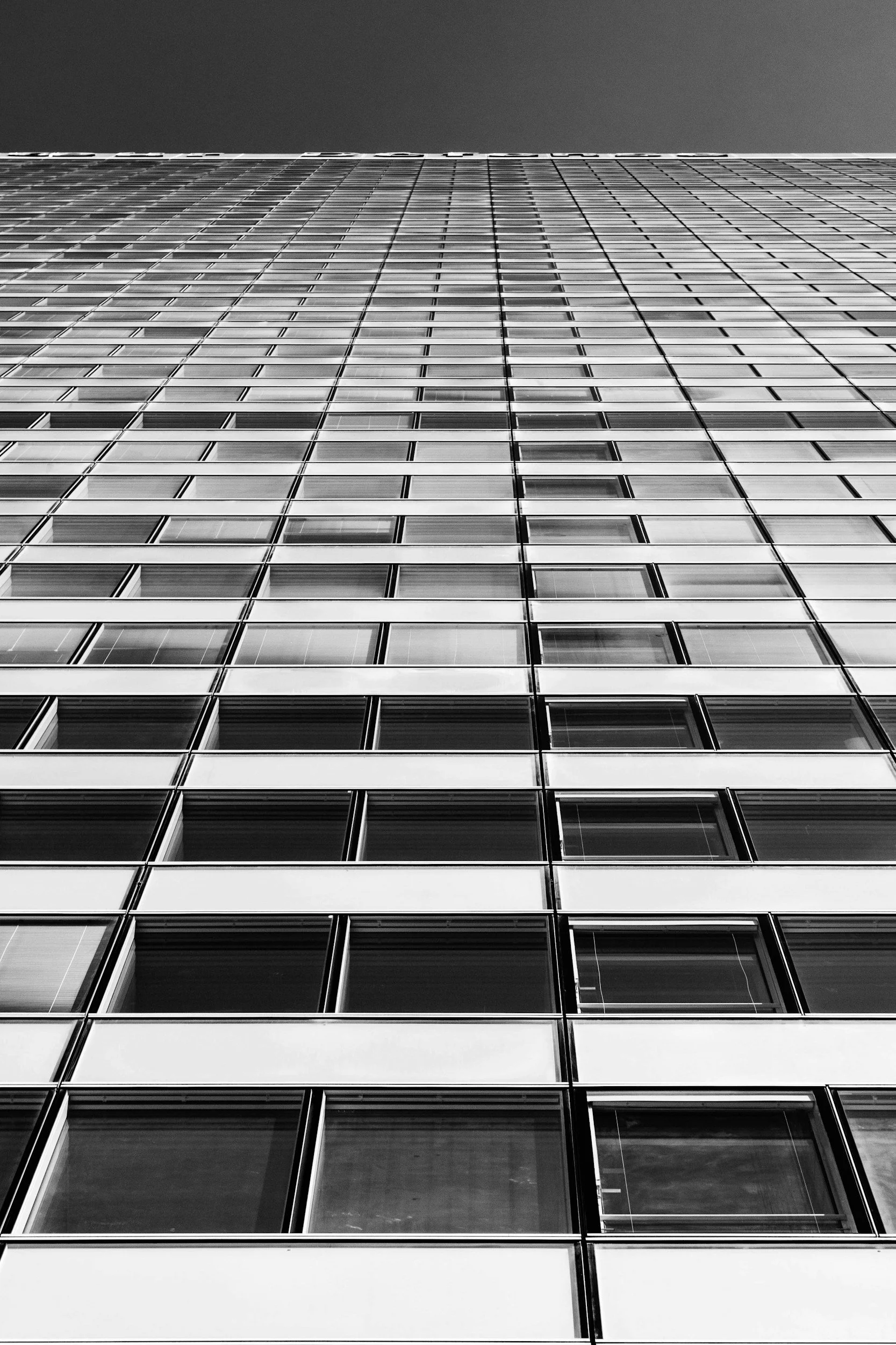 Black and white view of a modern skyscraper with glass windows.