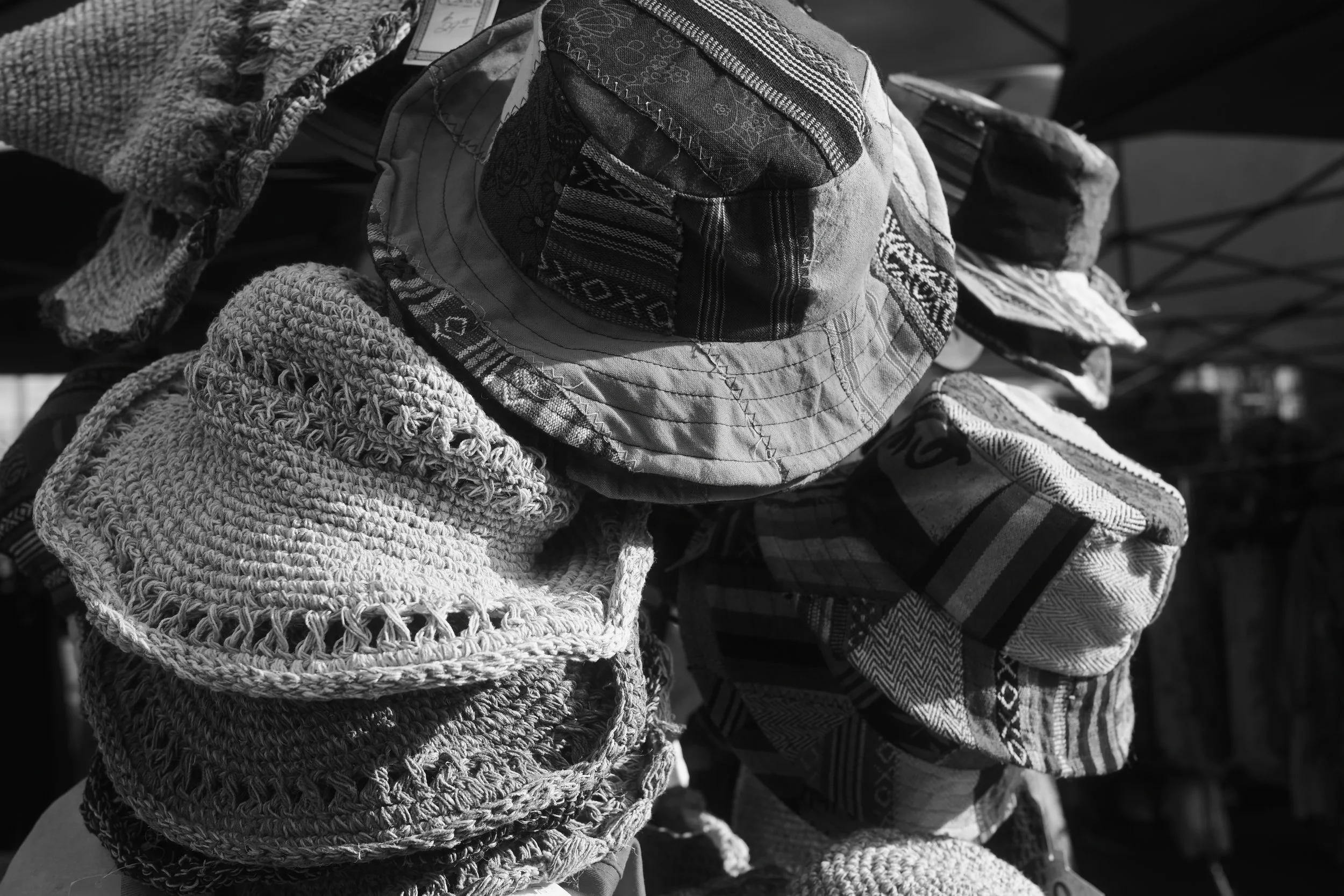 Black and white photo of various knitted and fabric hats stacked on display.
