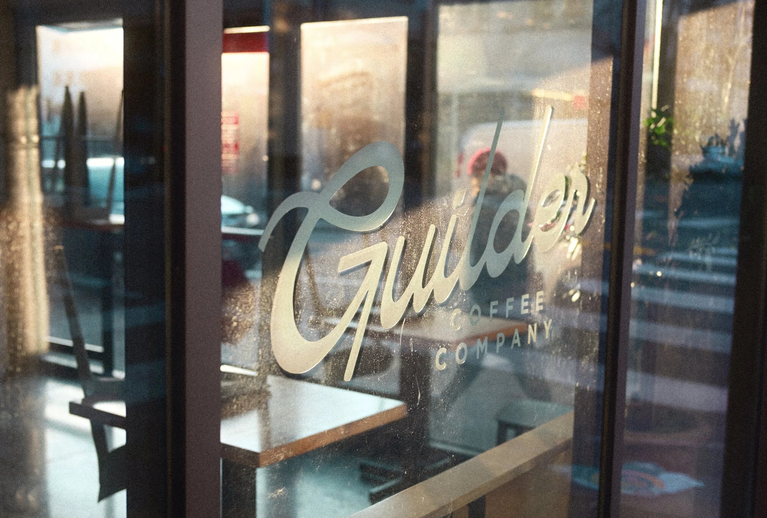 Close-up of a coffee shop window displaying the “Ephraim Coffee Company” logo with reflections of the street and interior.