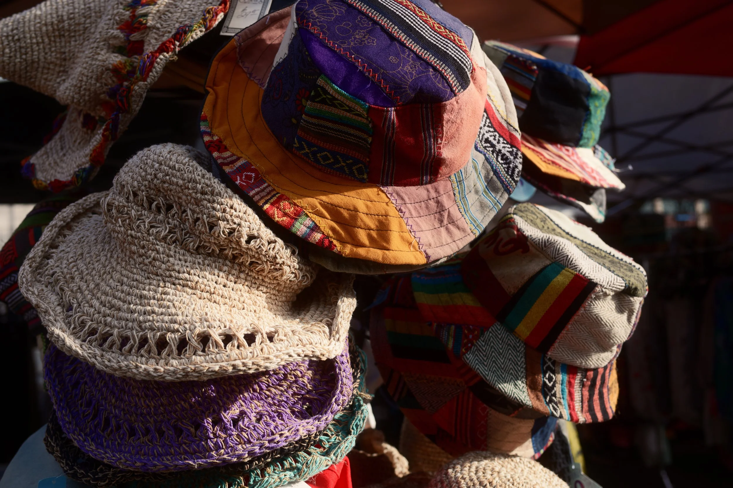 Display of colorful, patterned hats and scarves on a market stand.