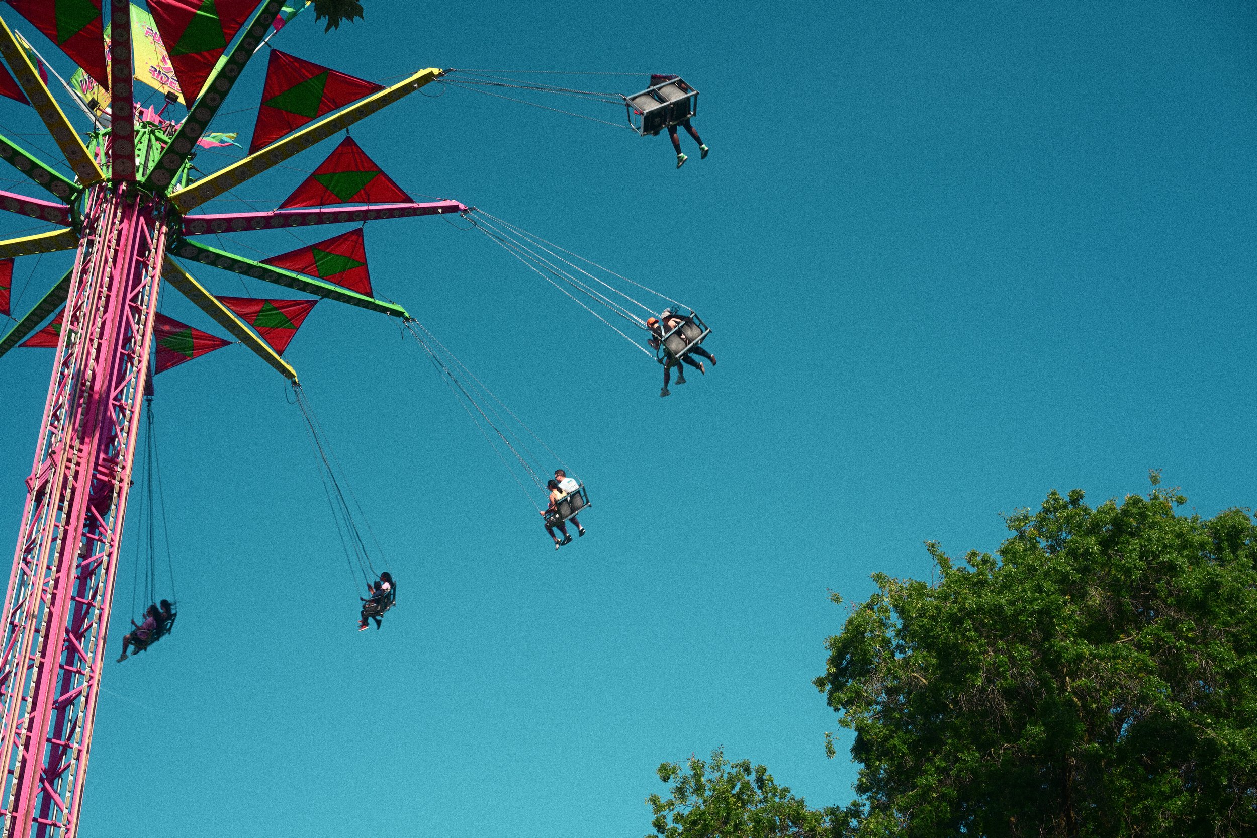 Colorful carnival swing ride with passengers suspended against a clear blue sky