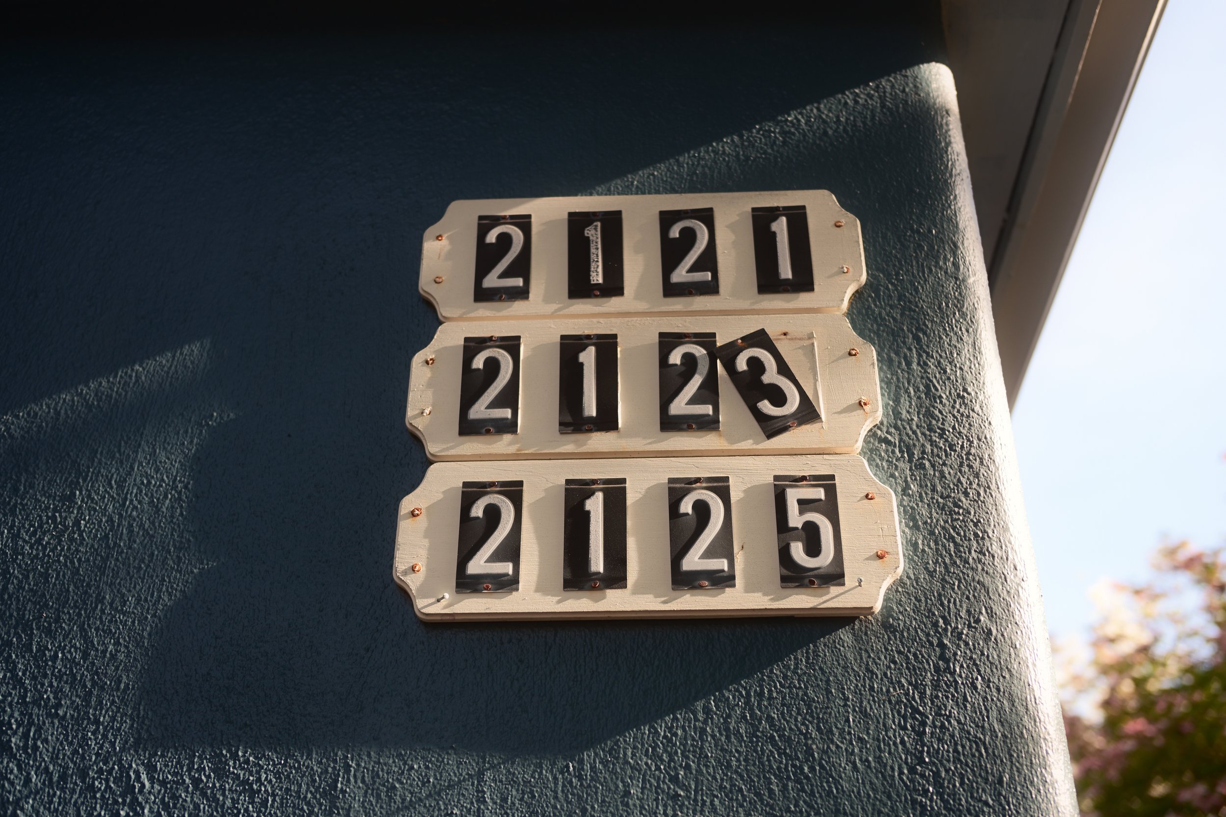 A vintage black and white flip clock displaying the time 22:21:23 mounted on a textured dark blue wall near a window.