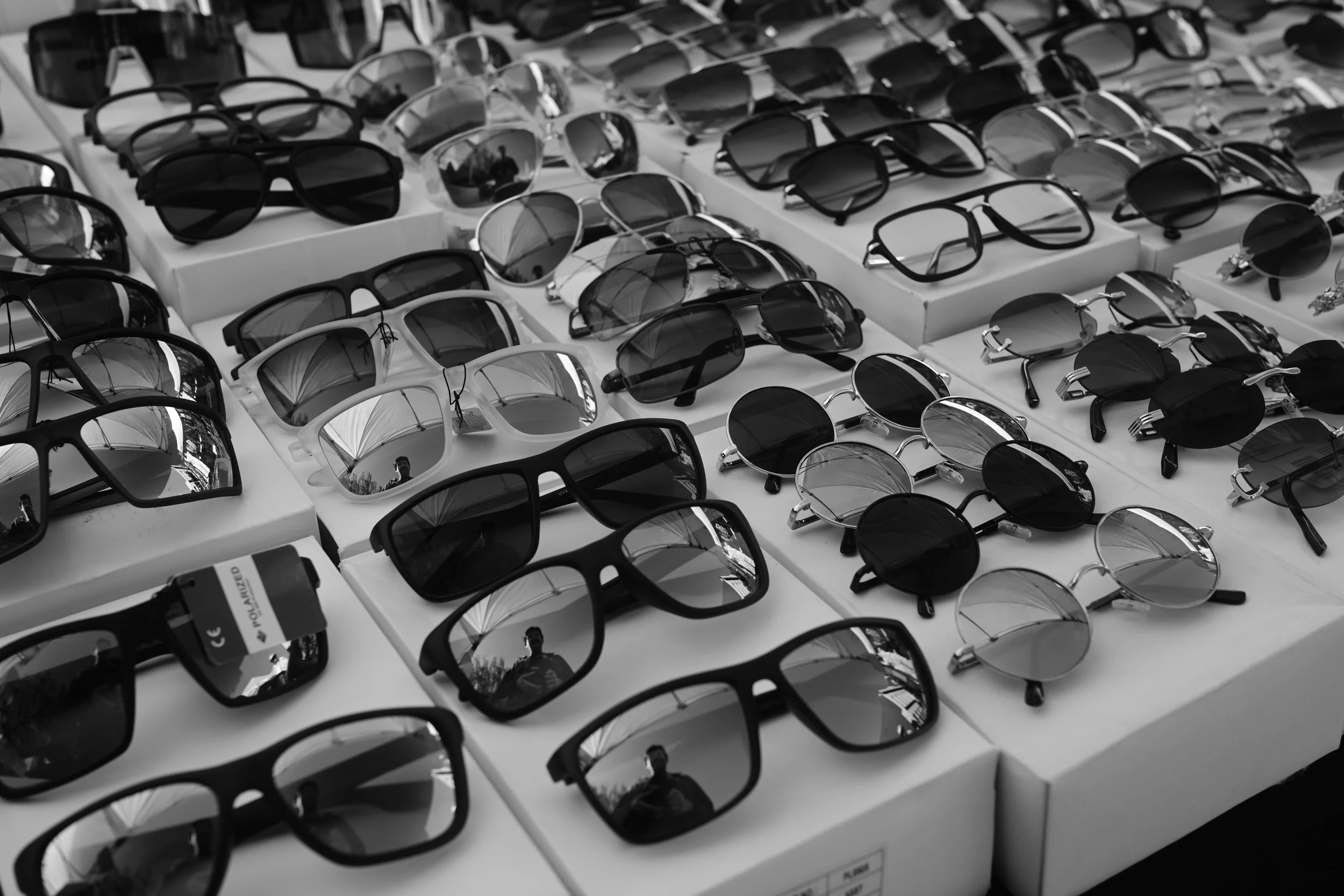 A display of various sunglasses and eyeglasses in different styles and sizes at what appears to be a store or market stall.