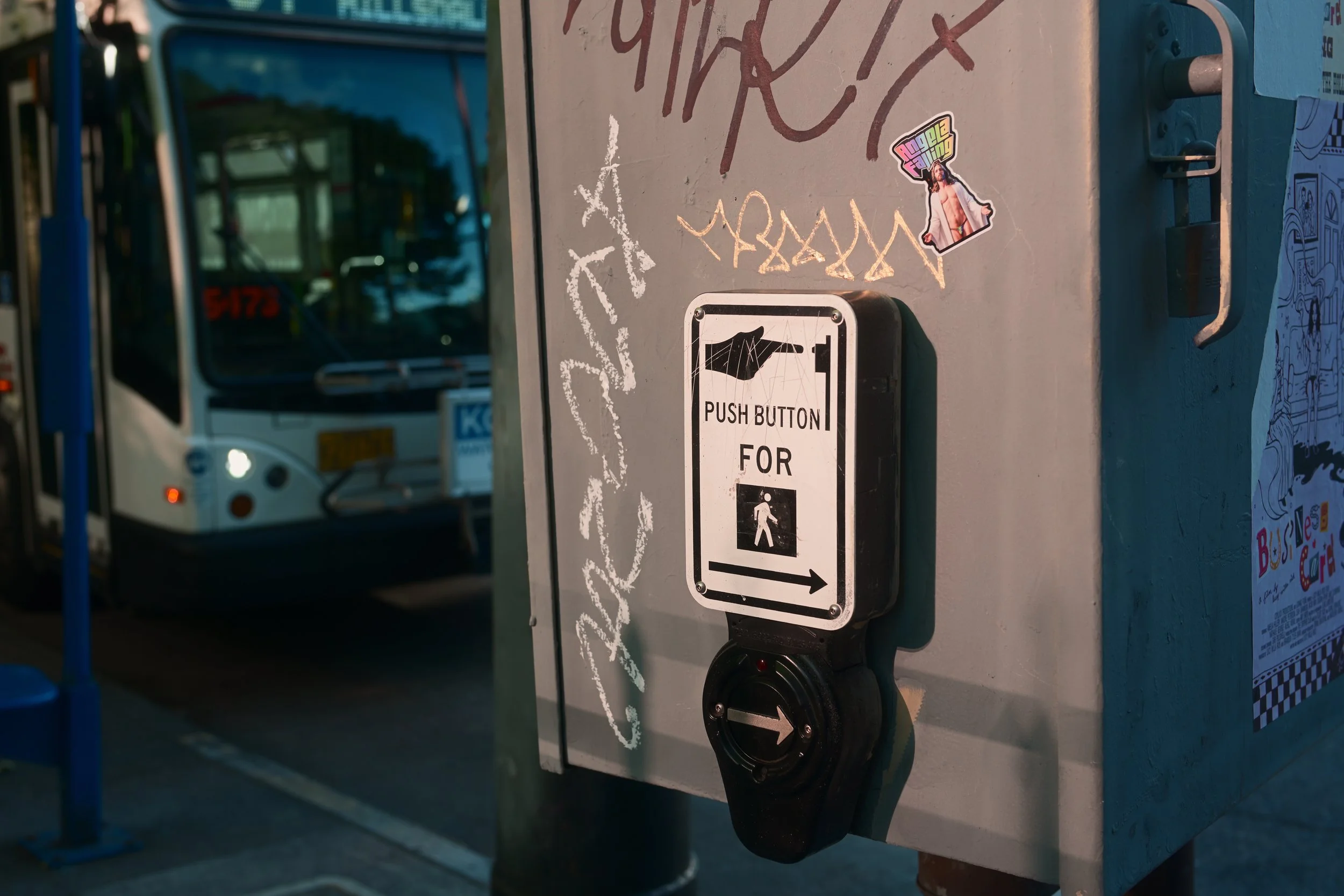 Close-up shot of a sign and push button on a vending or ticket machine with street scene reflected on the glass in the background.