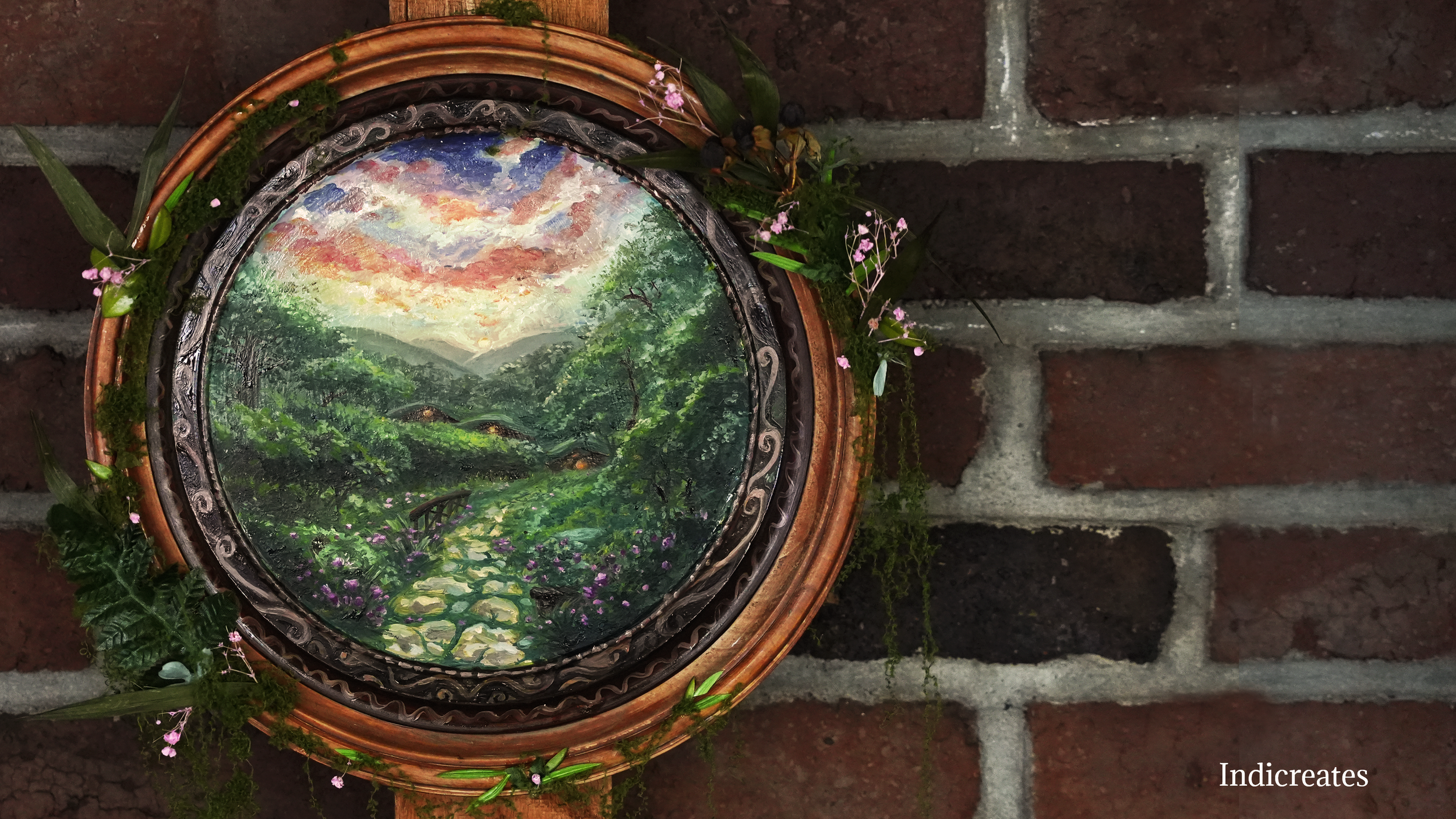 A decorative round painting of a lush green landscape with a stone pathway, flowing water, trees, and a colorful sky, surrounded by a wicker frame and small pink flowers hanging around it, mounted on a brick wall.