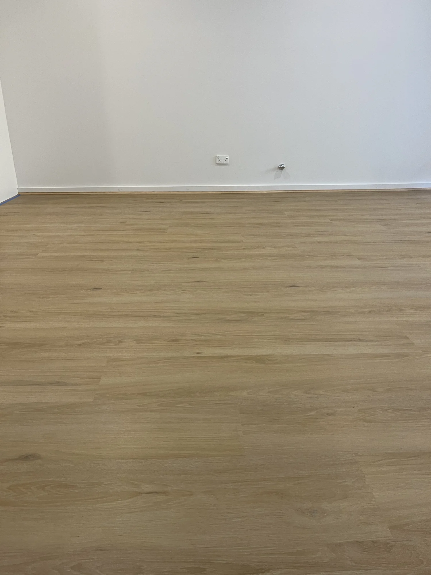 Empty room with light wood flooring, white walls, electrical outlets near the floor, one standard power outlet, and one coaxial cable outlet.