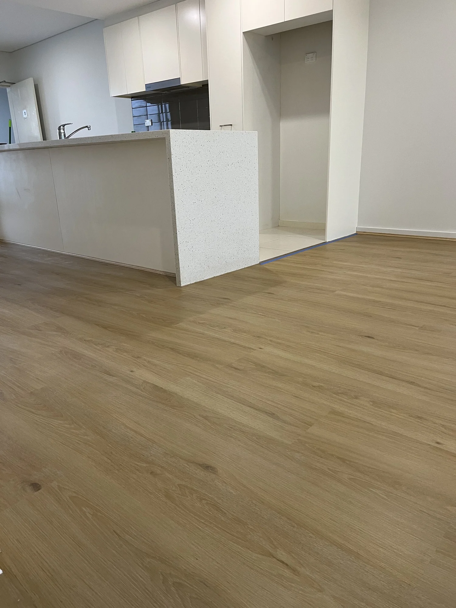 Empty kitchen with white cabinets, a countertop, and light wood flooring.