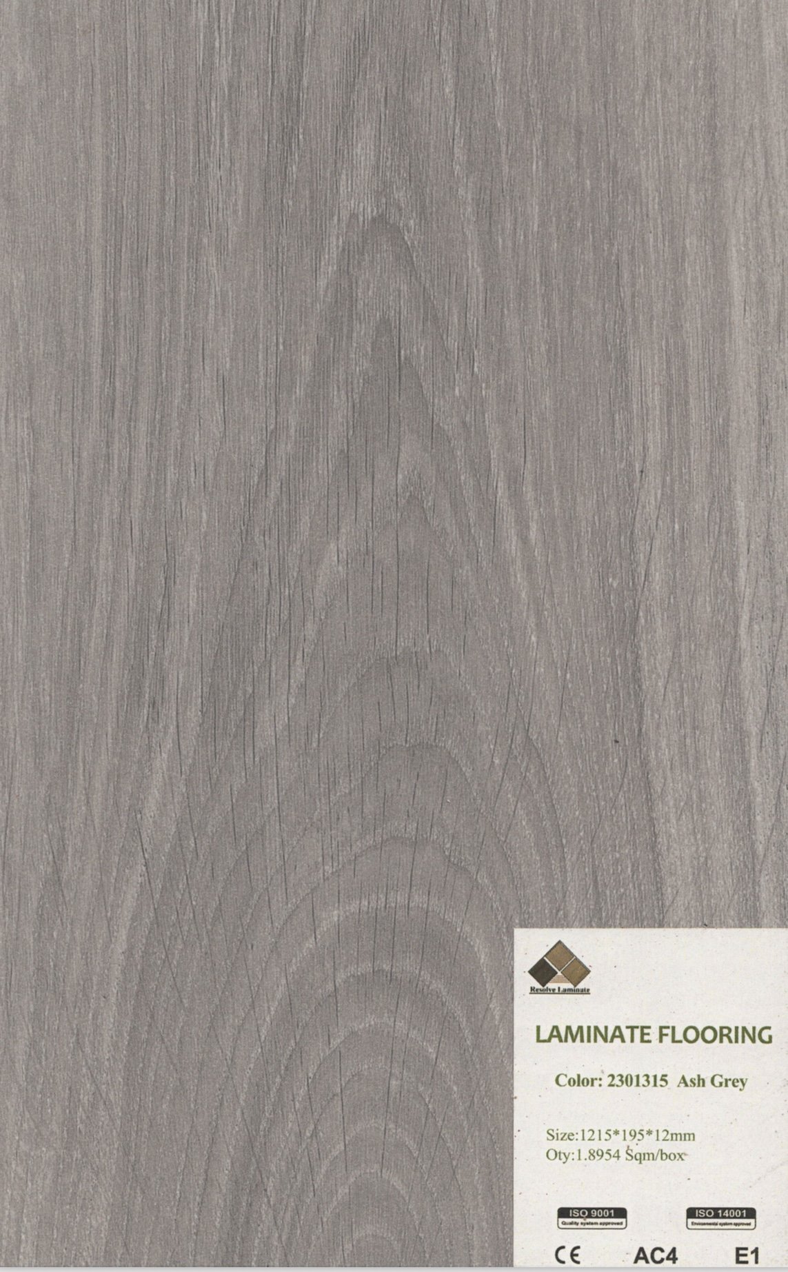 A sample laminated flooring with a light ash grey wood grain pattern and a small label in the bottom right corner indicating it is laminate flooring in ash grey color.