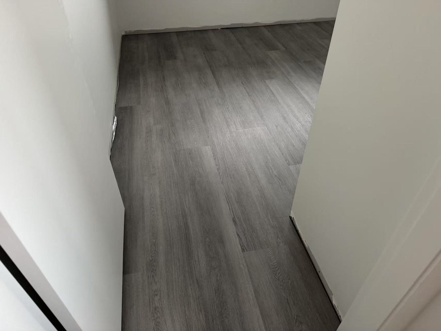 Intersection of hardwood flooring and a door frame in a room with white walls.