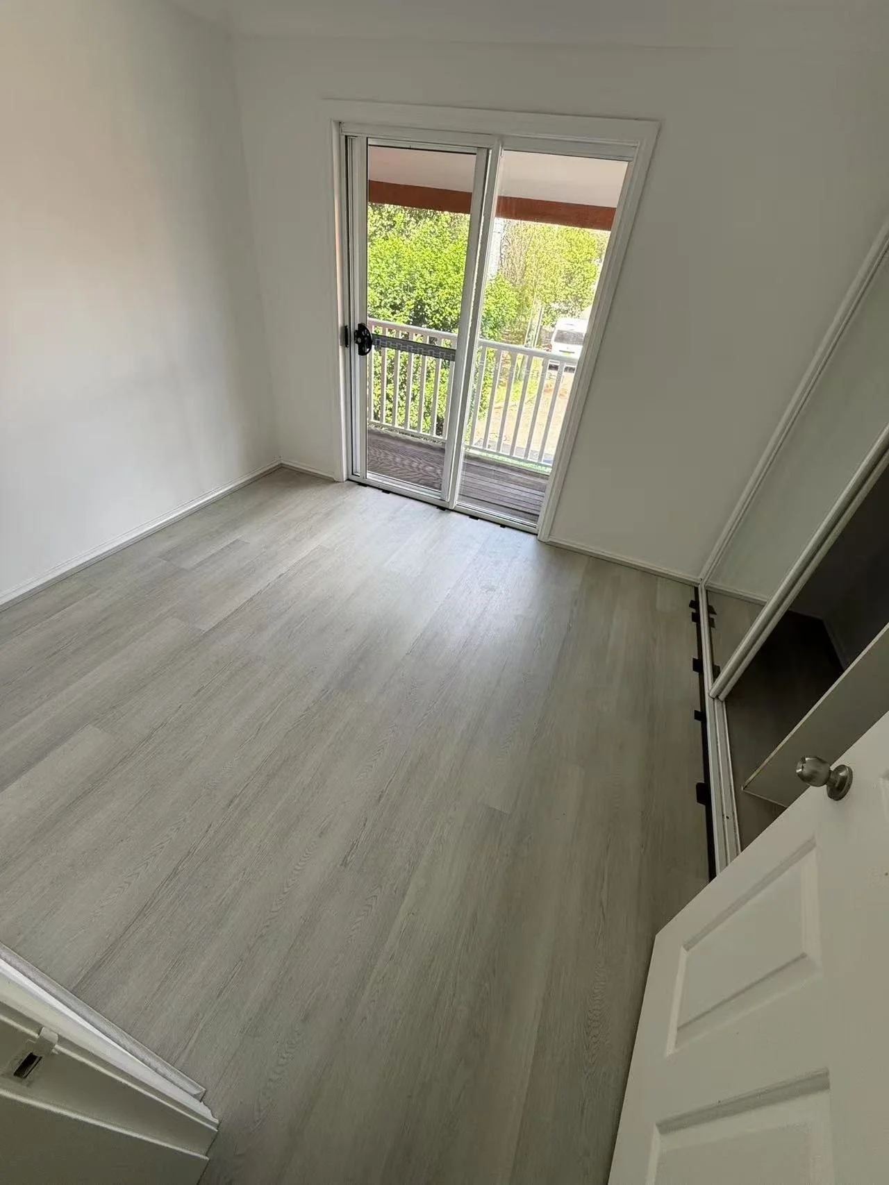Empty room with sliding glass door leading to a balcony, light-colored flooring, and an open closet door.