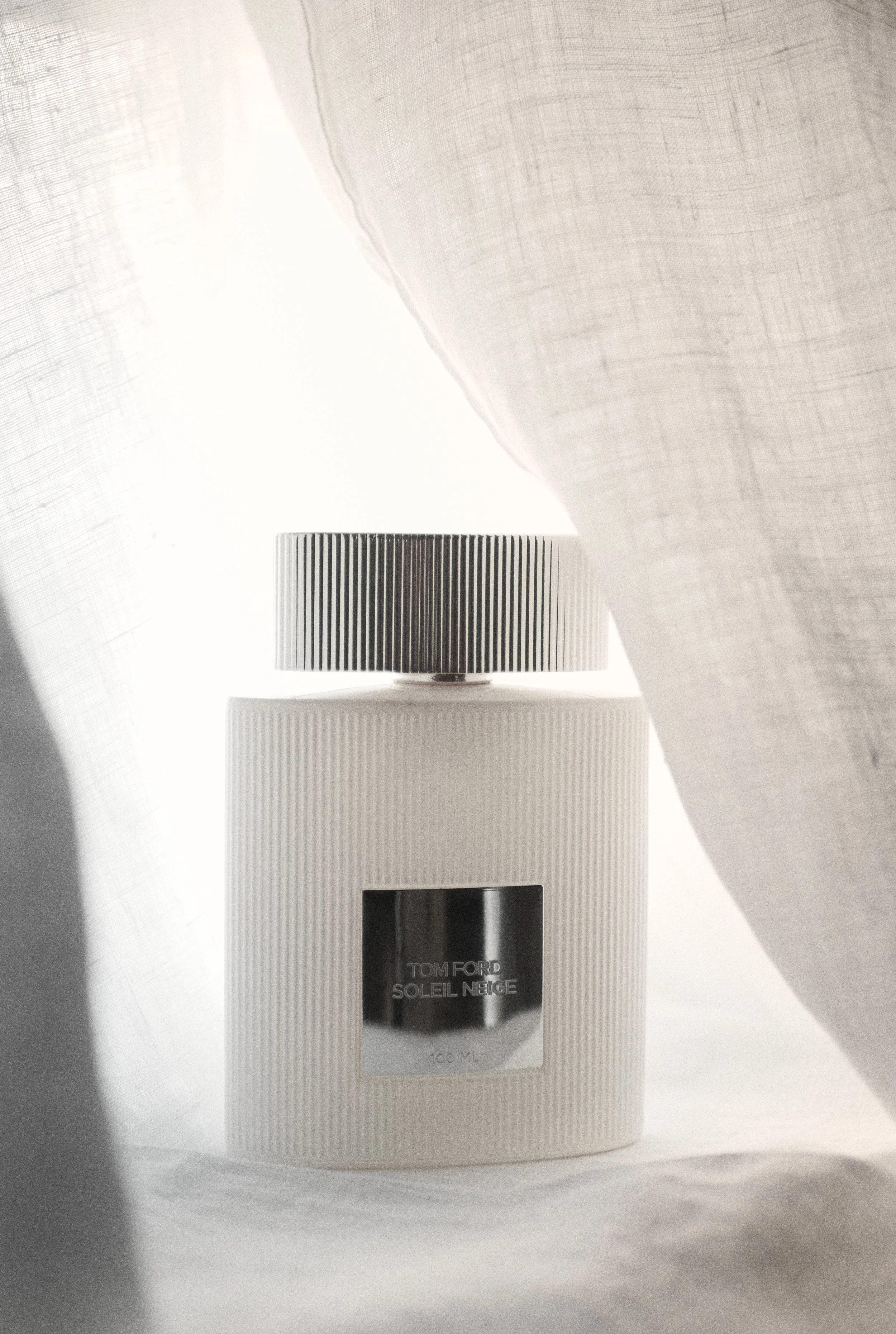 Eine Tube von Tom Ford Soleil Neige Sonnencreme steht auf einer weißen Oberfläche vor hellem Hintergrund.