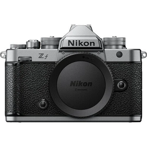 Nikon Z fc mirrorless camera with a silver and black body, featuring textured grip, control dials, and a lens mount cover.