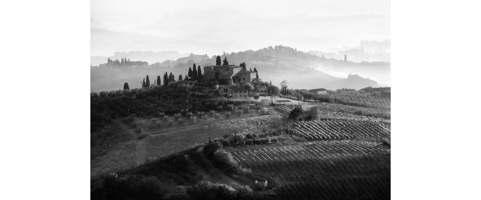 Black and white photograph of a Tuscan villa with morning fog in Tuscany, Italy by Bret Culp, featured in the testimonials section on the homepage.