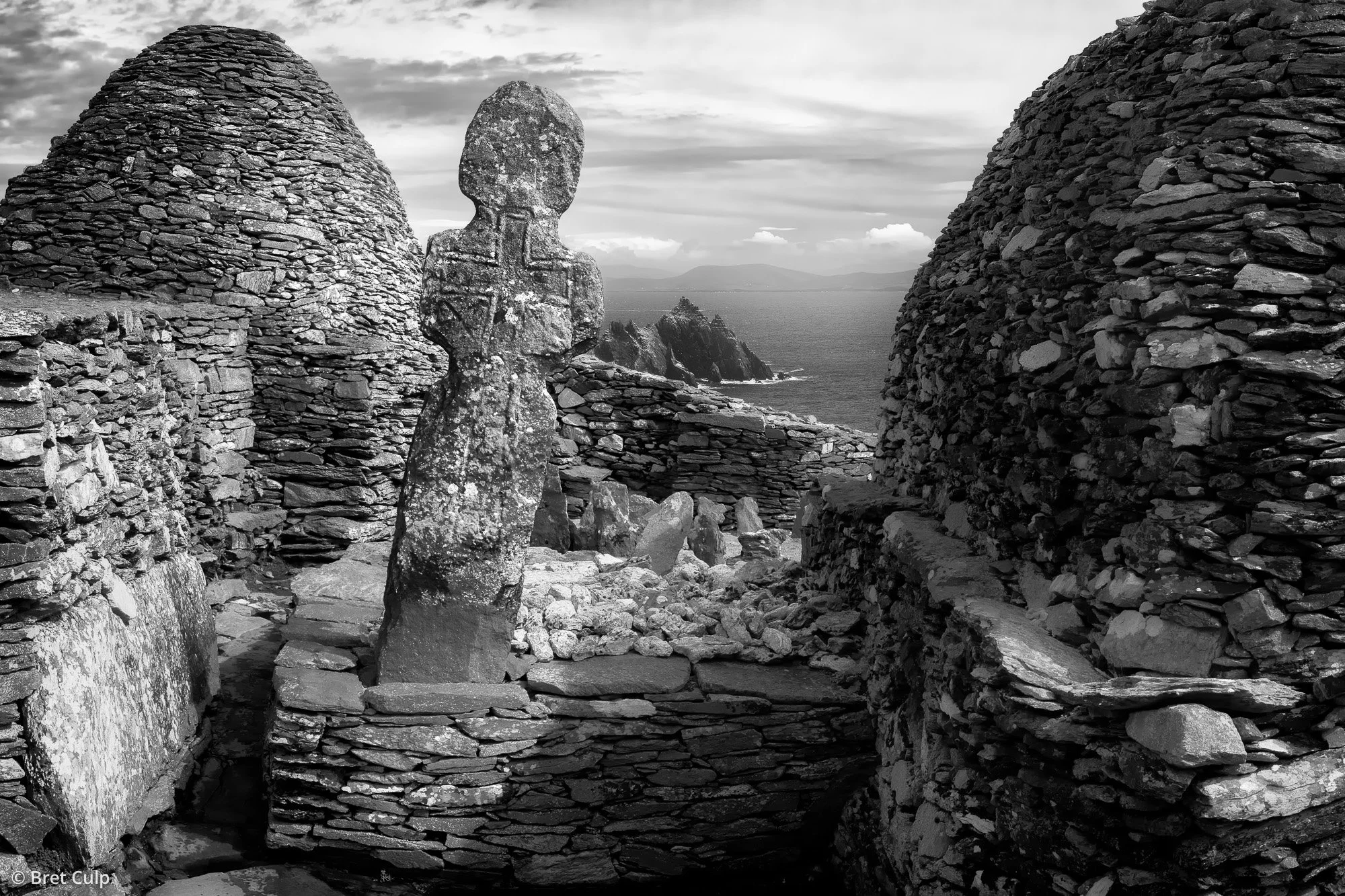 Ancient stone cross, The Priest’s Stone, in Skellig Michael’s monastic graveyard, Ireland, under dramatic coastal light.