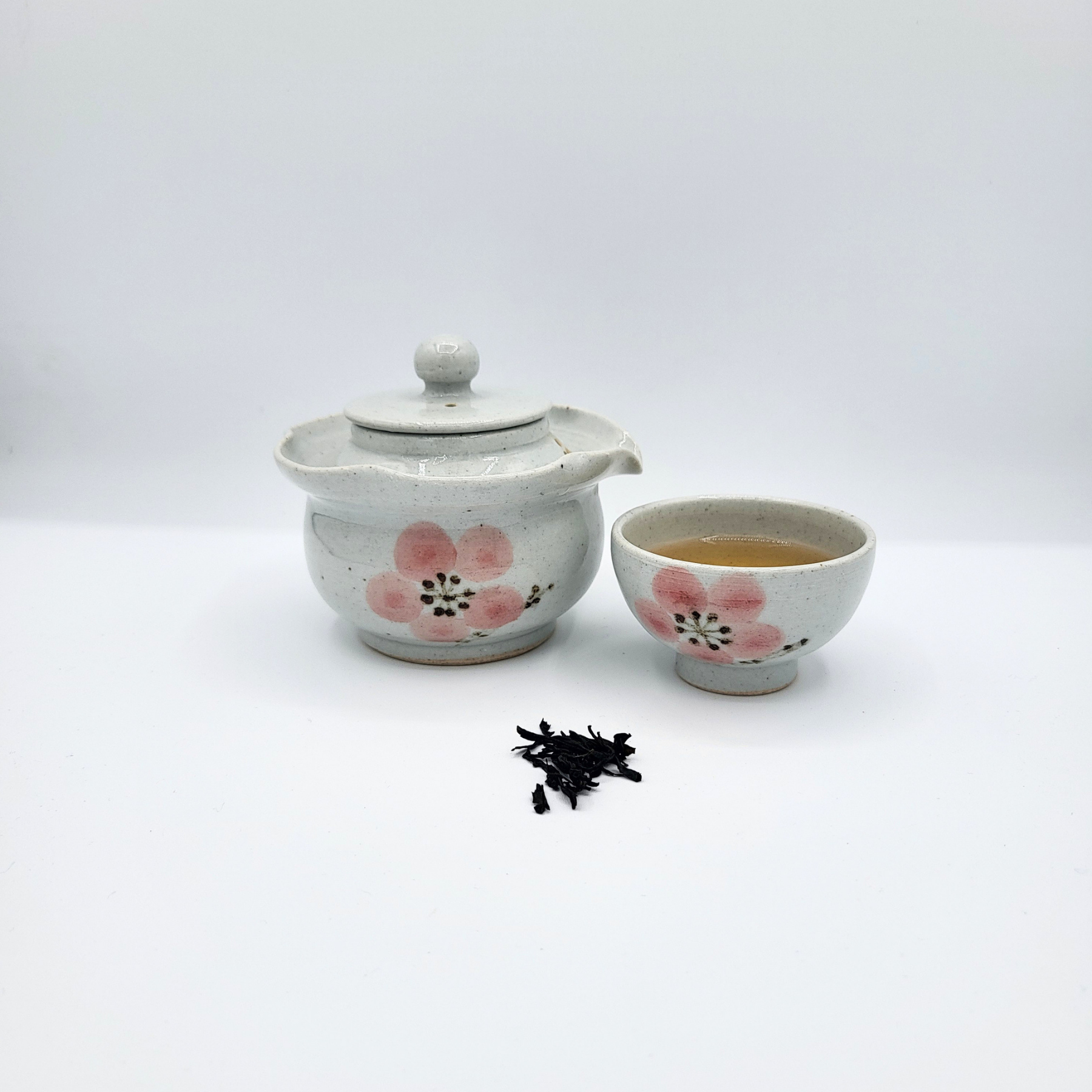 Korean-style gaiwan and cup with brewed Hong Cha and a mound of loose leaf tea leaves in front.