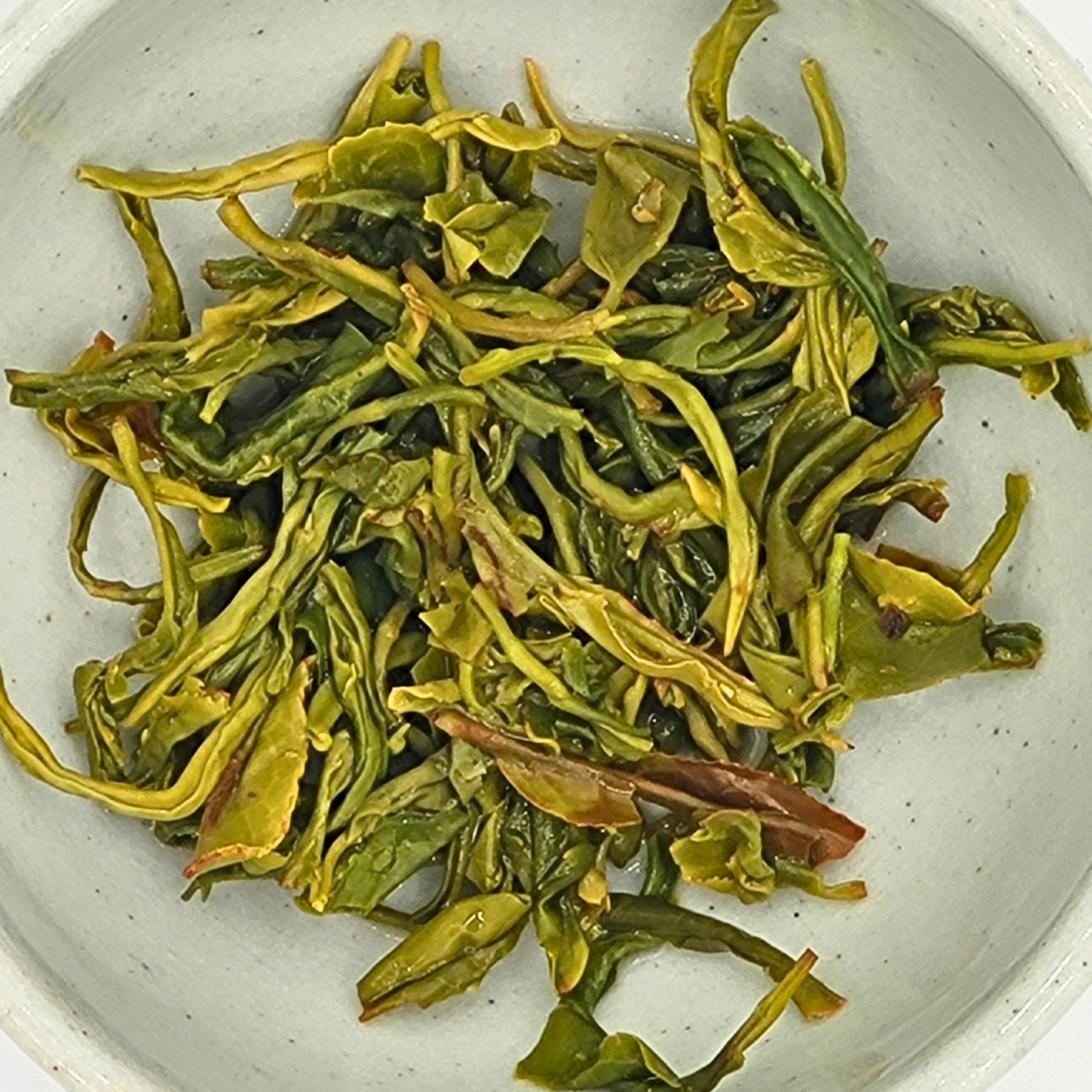 Infused leaves of Woojeon tea in a small light-glazed cup.