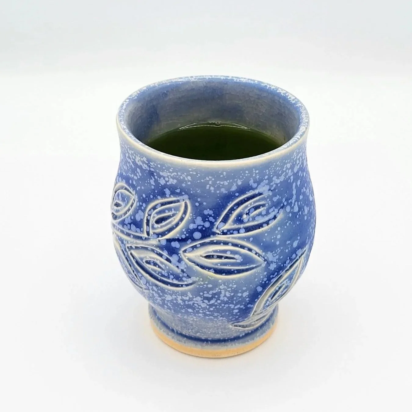 Rich green infused yuzu kukicha with matcha tea in a handmade blue yunomi with leaves carved into the clay.