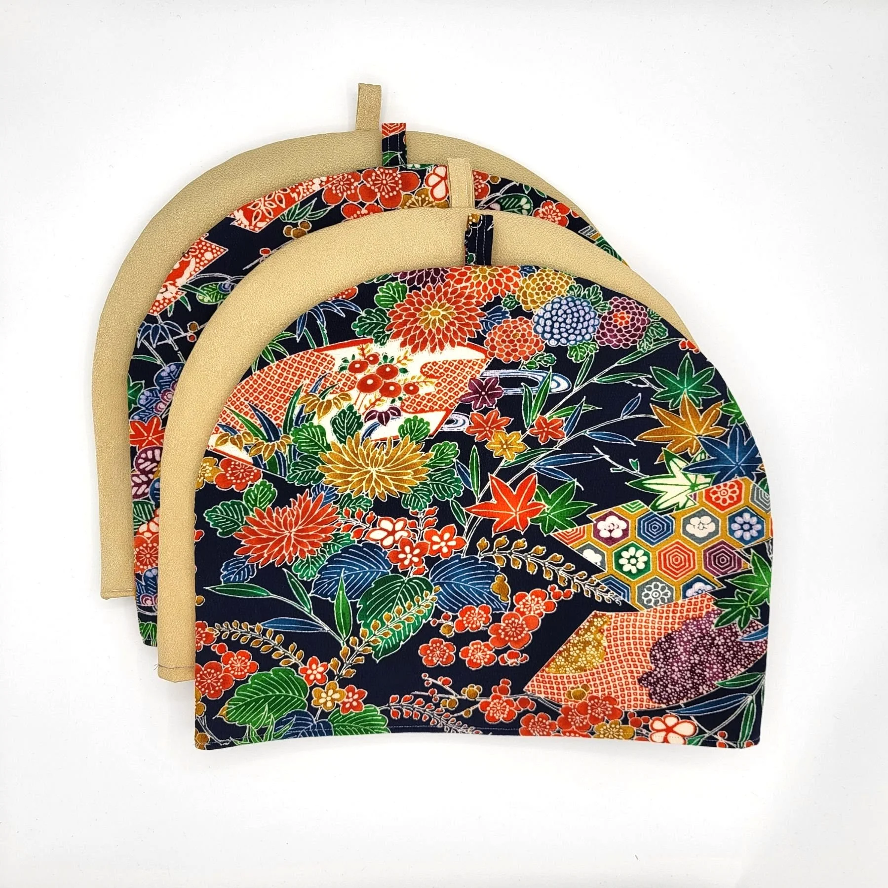 Four large patterned kimono silk tea cozies stacked and displayed flat, one on top of the other.