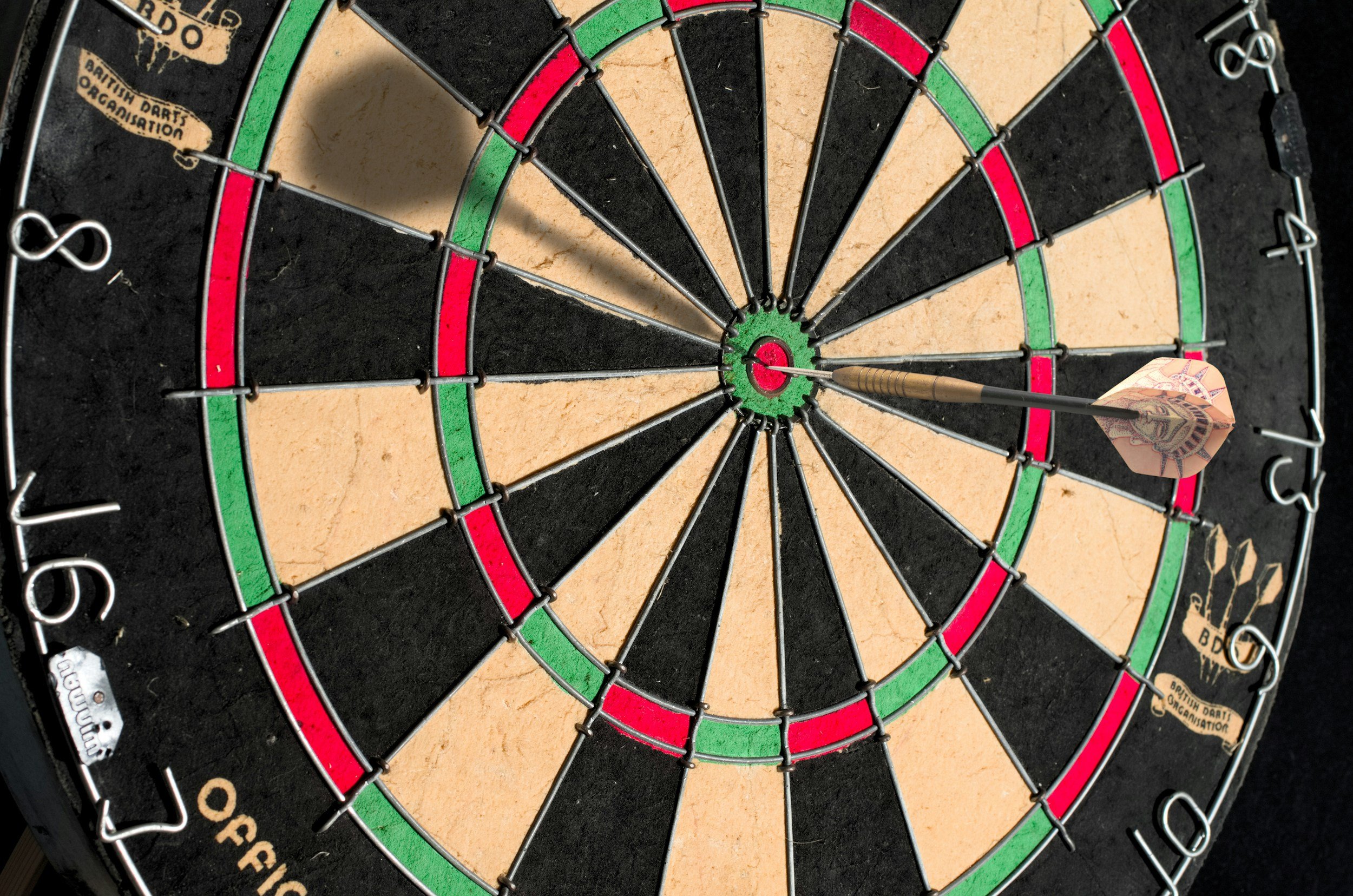 Close-up of a dartboard with a dart hitting the bullseye.