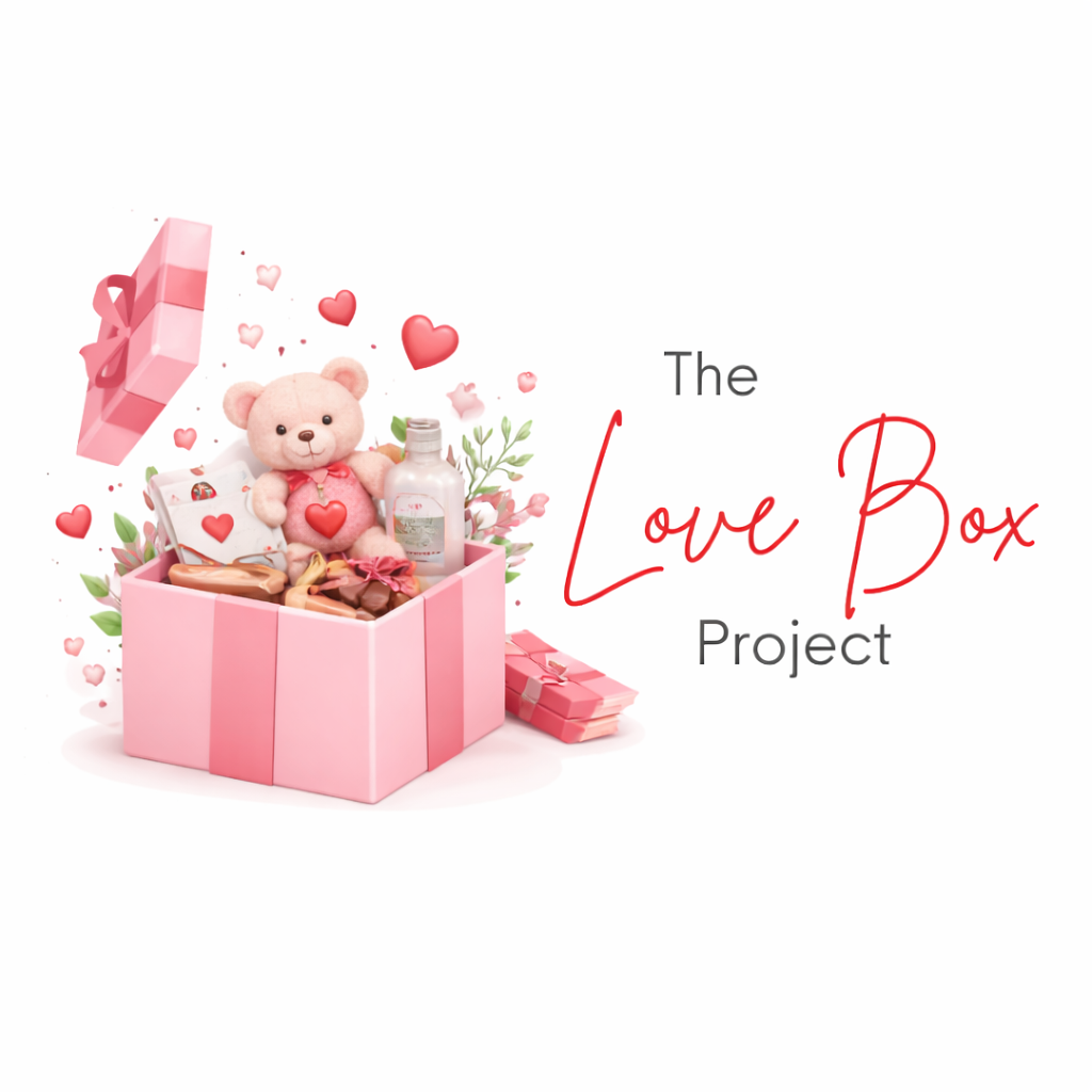 A pink gift box with a teddy bear, chocolates, a bottle, and greenery inside. The box has a pink ribbon, and there's a small pink gift box nearby. Floating hearts surround the setup. To the right, text reads "The Love Box Project" in gray and red fonts.